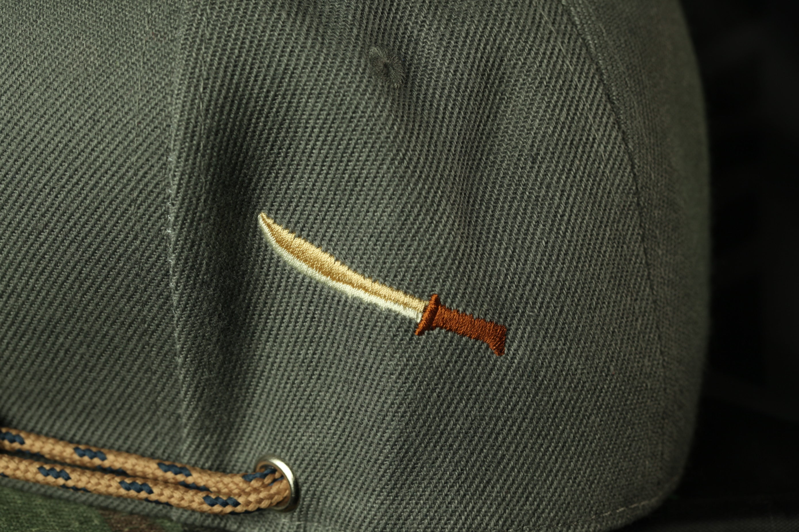 A close-up view of a gray fabric with a small embroidered knife handle on it.