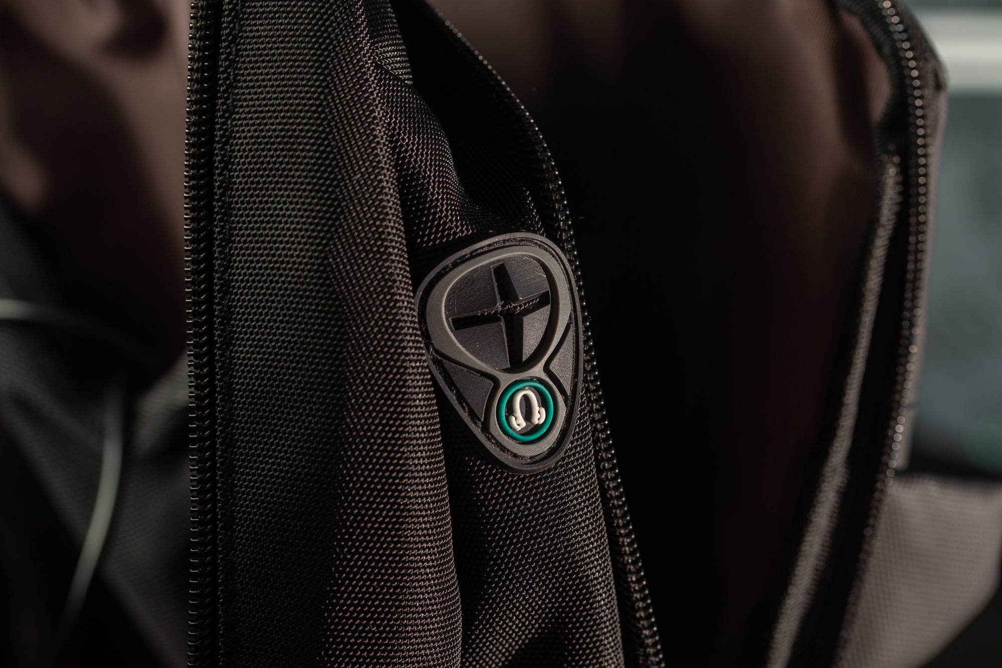 A close-up view of a black fabric, possibly a piece of clothing or a bag, with a small green and black logo or emblem attached to it.