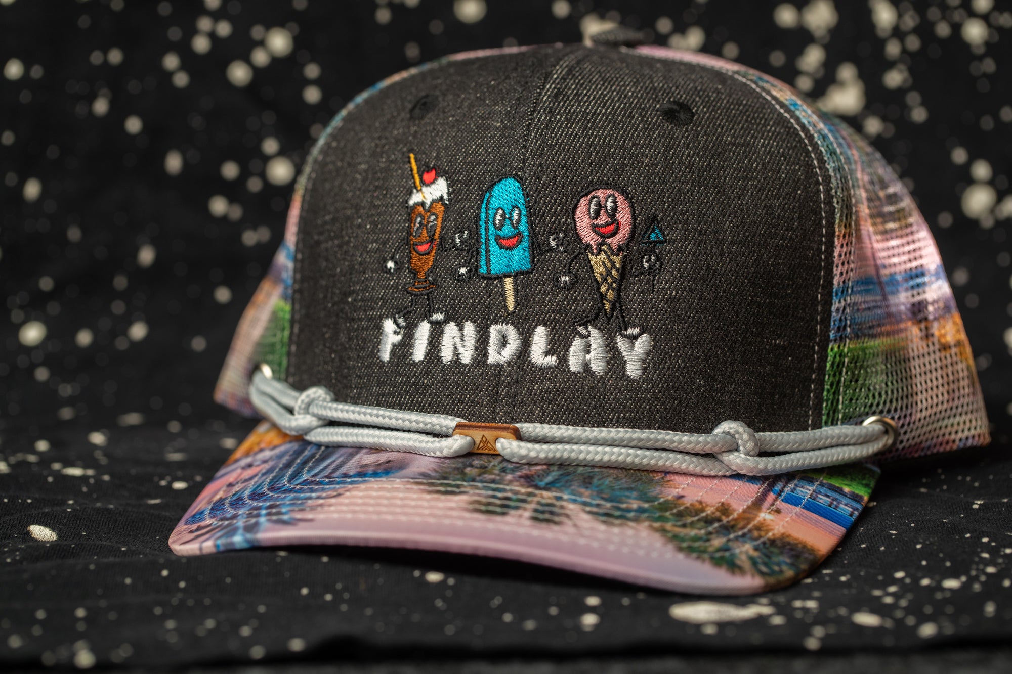 A colorful baseball cap with a cartoon ice cream cone design and the word "FINDlay" printed on it.