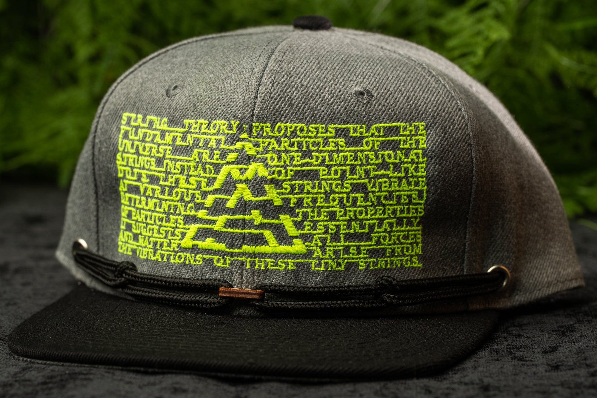 A gray baseball cap with a yellow and green design on the front, featuring a repeating pattern of text and graphics.