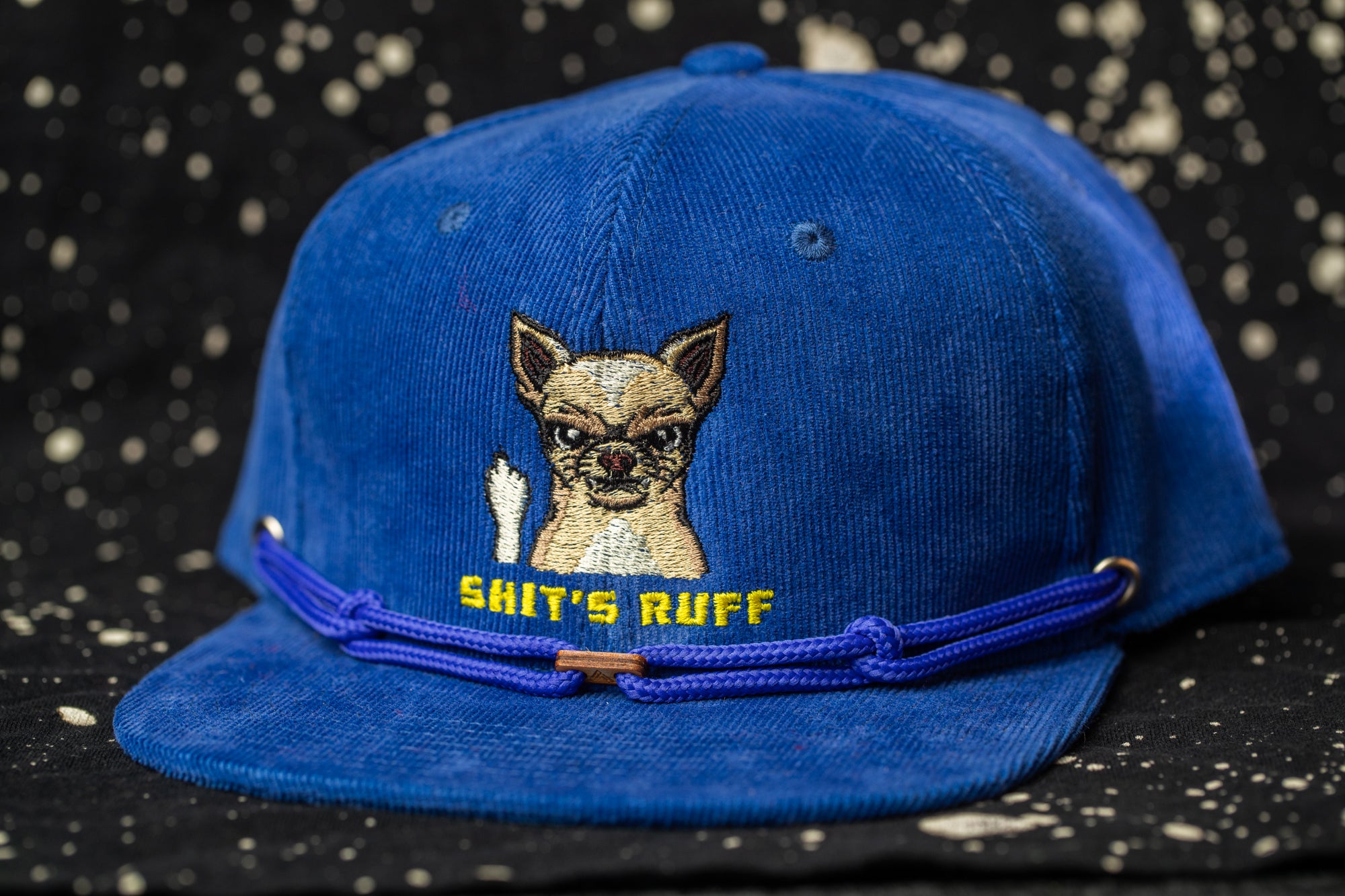 A blue baseball cap with a cartoon image of a dog and the text "SHIT'S RUFF" printed on it.
