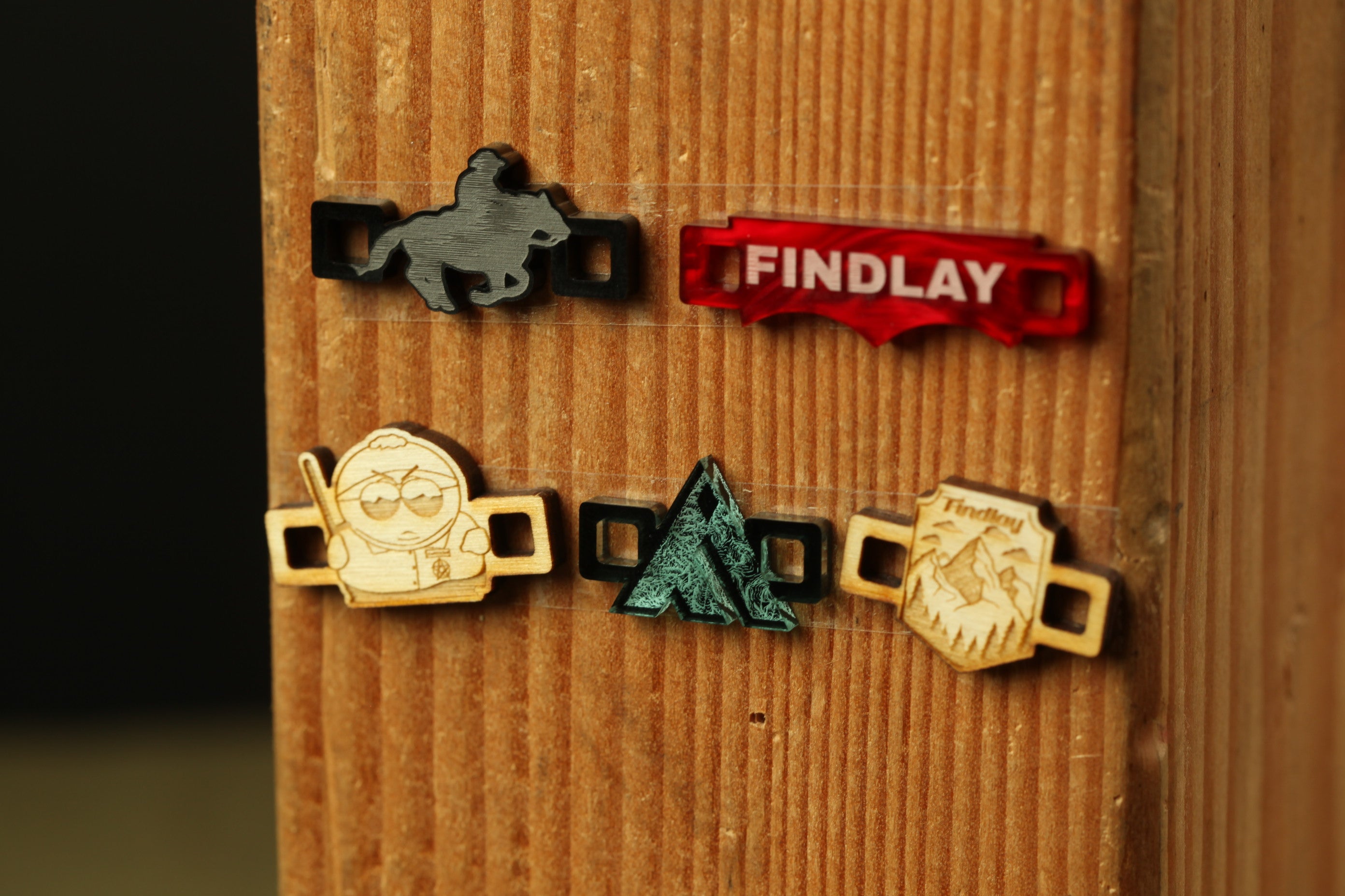a wooden surface with several wooden charms or stickers attached to it. The charms appear to be of different shapes and sizes, and they are arranged in a row. The image does not contain any text or specific details about the objects, and it does not depict any actions or movements. The focus of the image is on the wooden surface and the wooden charms.