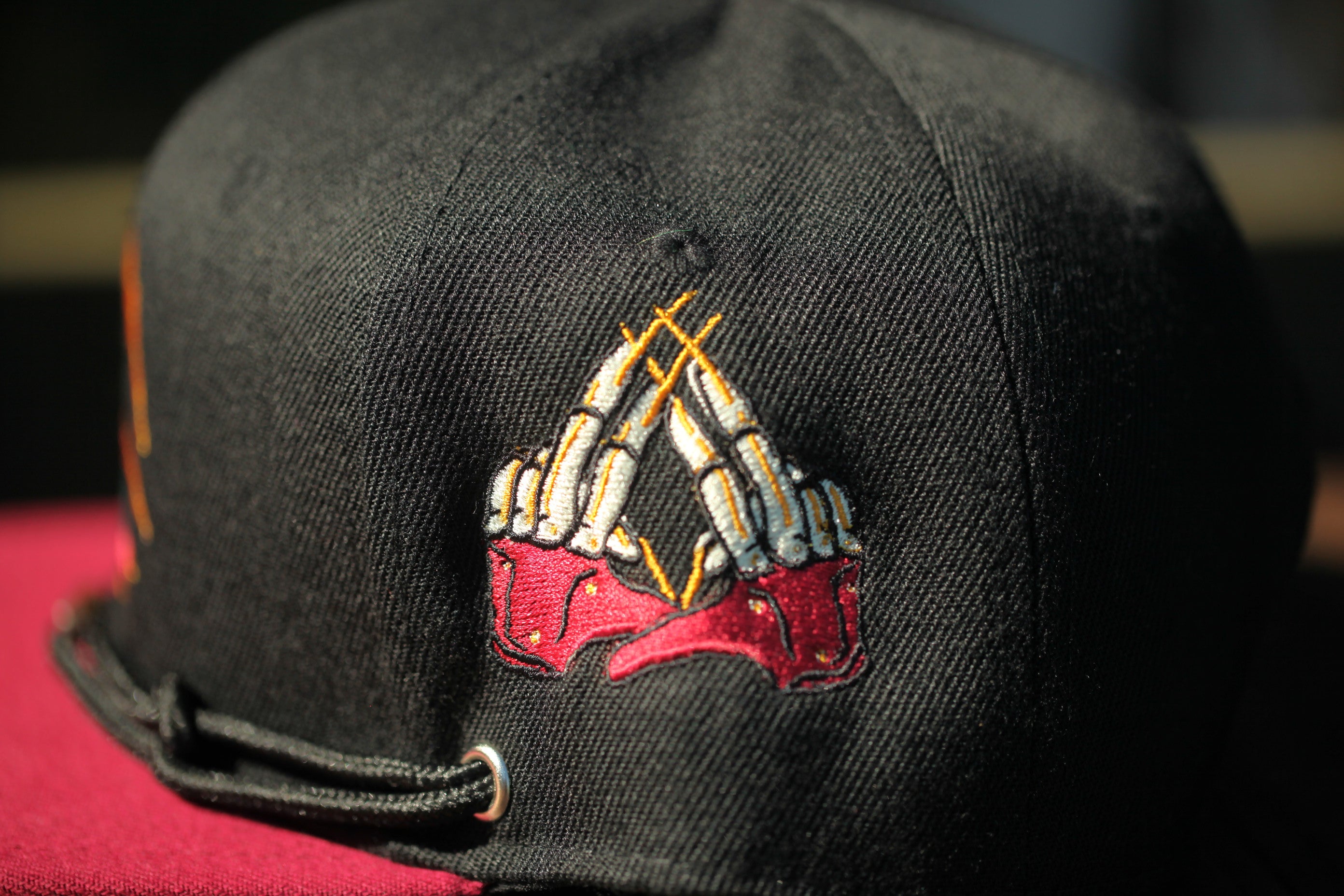 A close-up view of a black baseball cap with a unique embroidered design on the front.