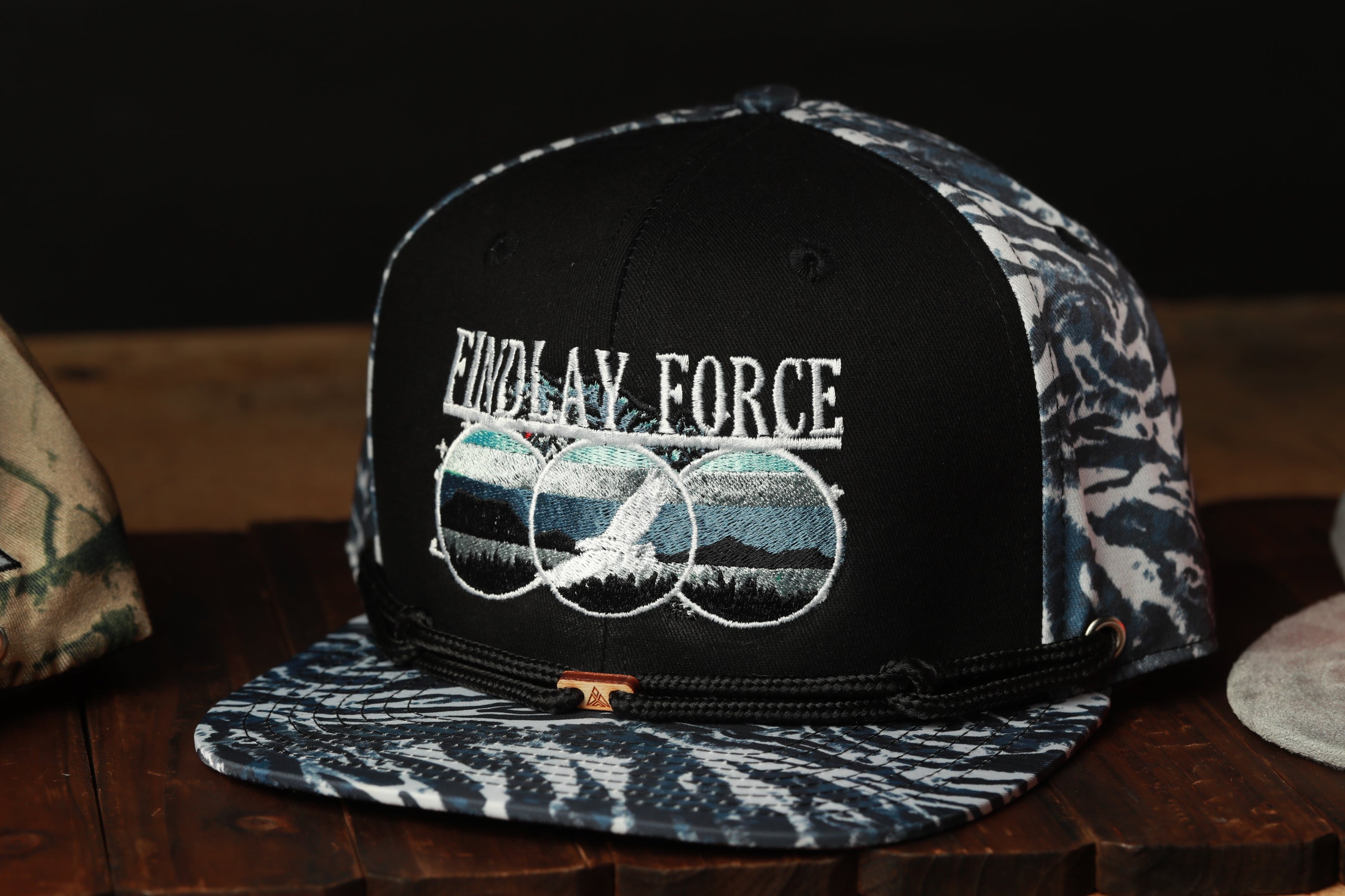 A black baseball cap with a patterned design and the text "FINDLAY FORCE" printed on it.