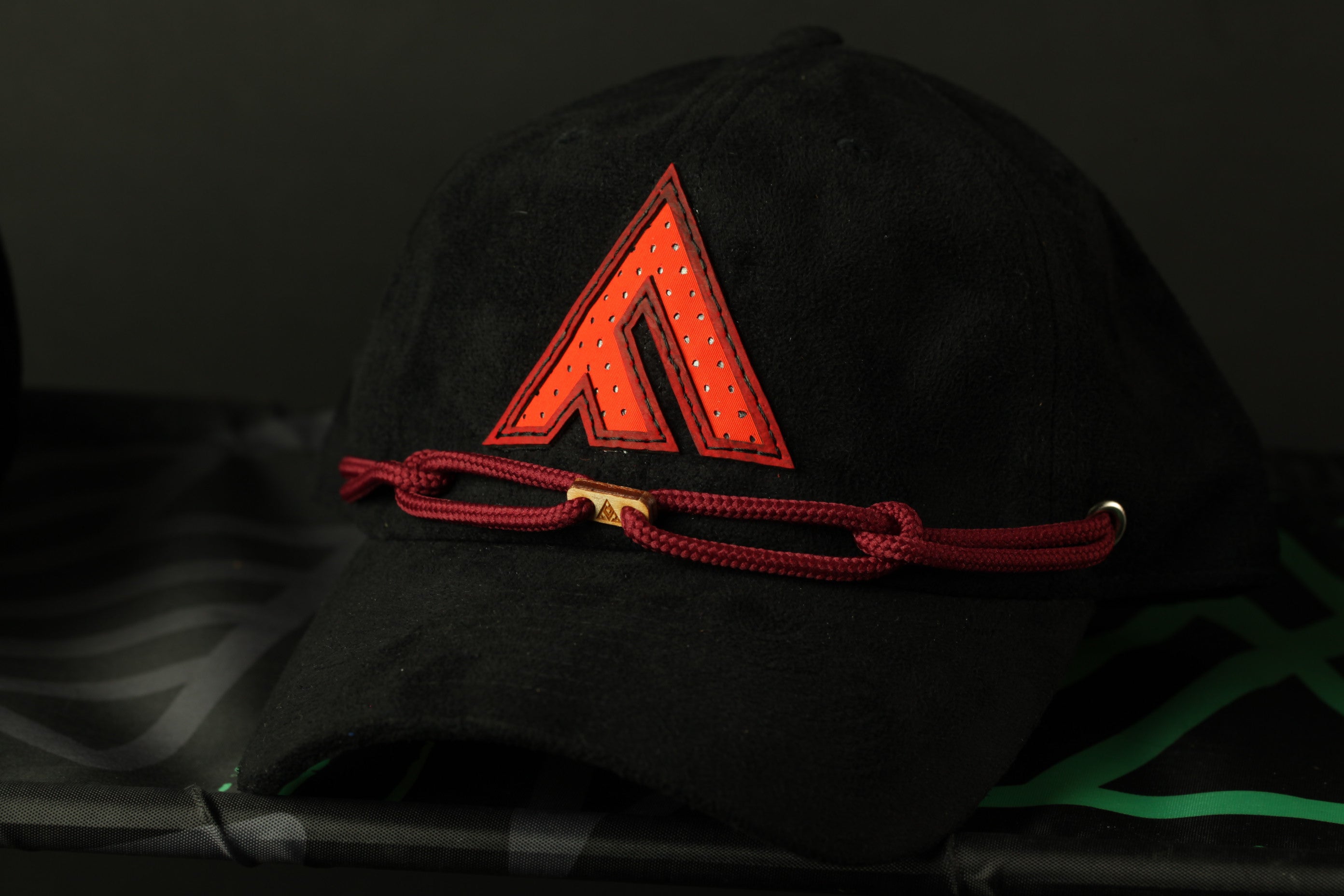 A black baseball cap with a red triangle logo on the front, resting on a black surface.