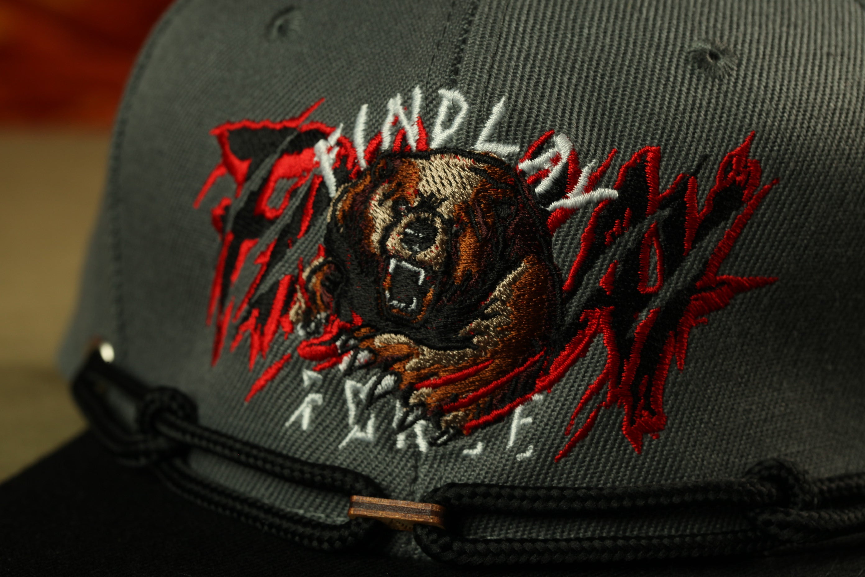 A close-up of a gray baseball cap with a graphic design featuring a fierce-looking bear.
