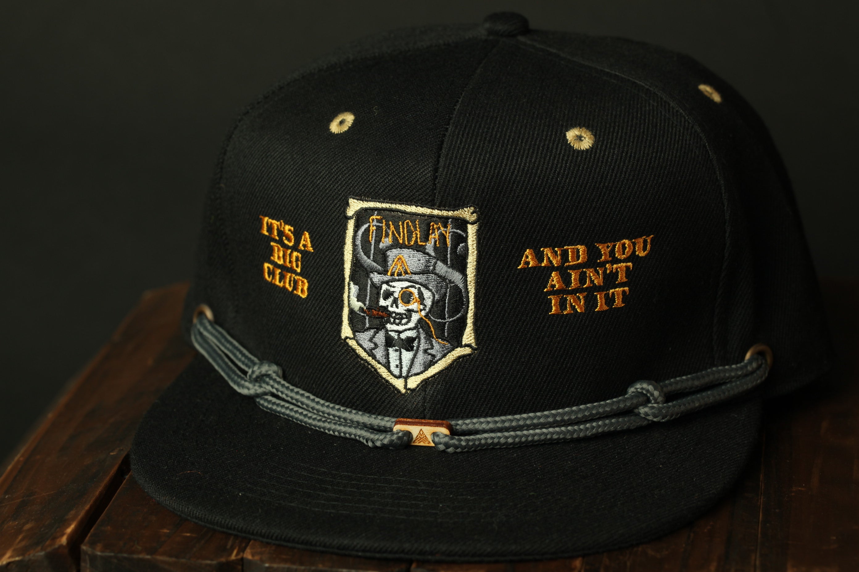 A black baseball cap with a skull and crossbones design, and text on the front.