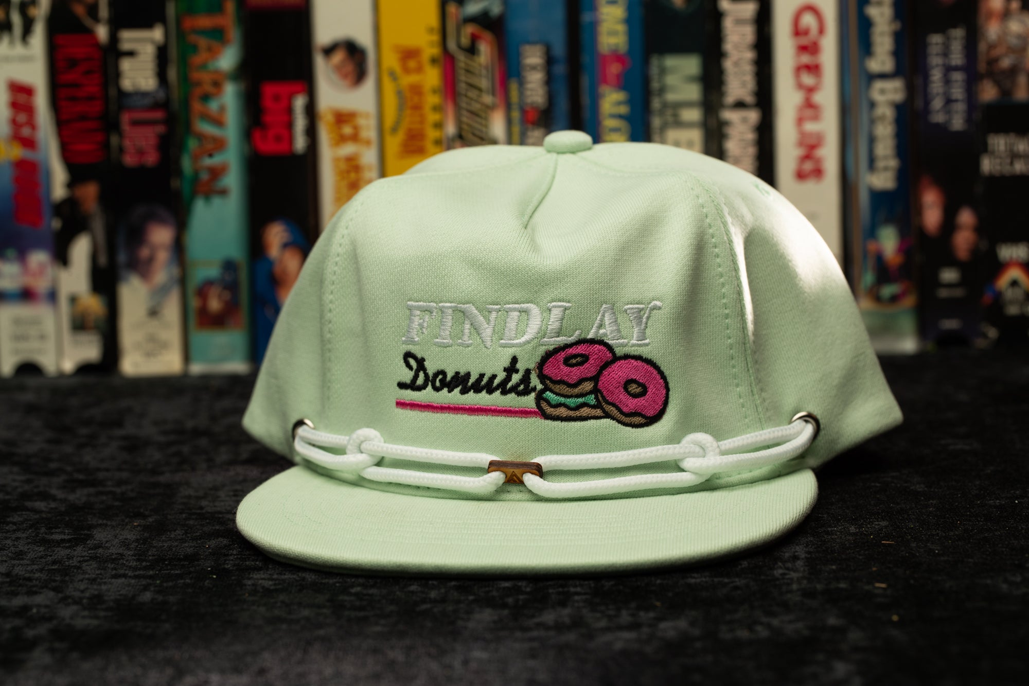 a green hat with a pink donut embroidered on it