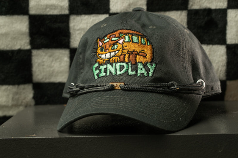 A black baseball cap with a cartoon cat design and the word "FINDLAY" printed on it.