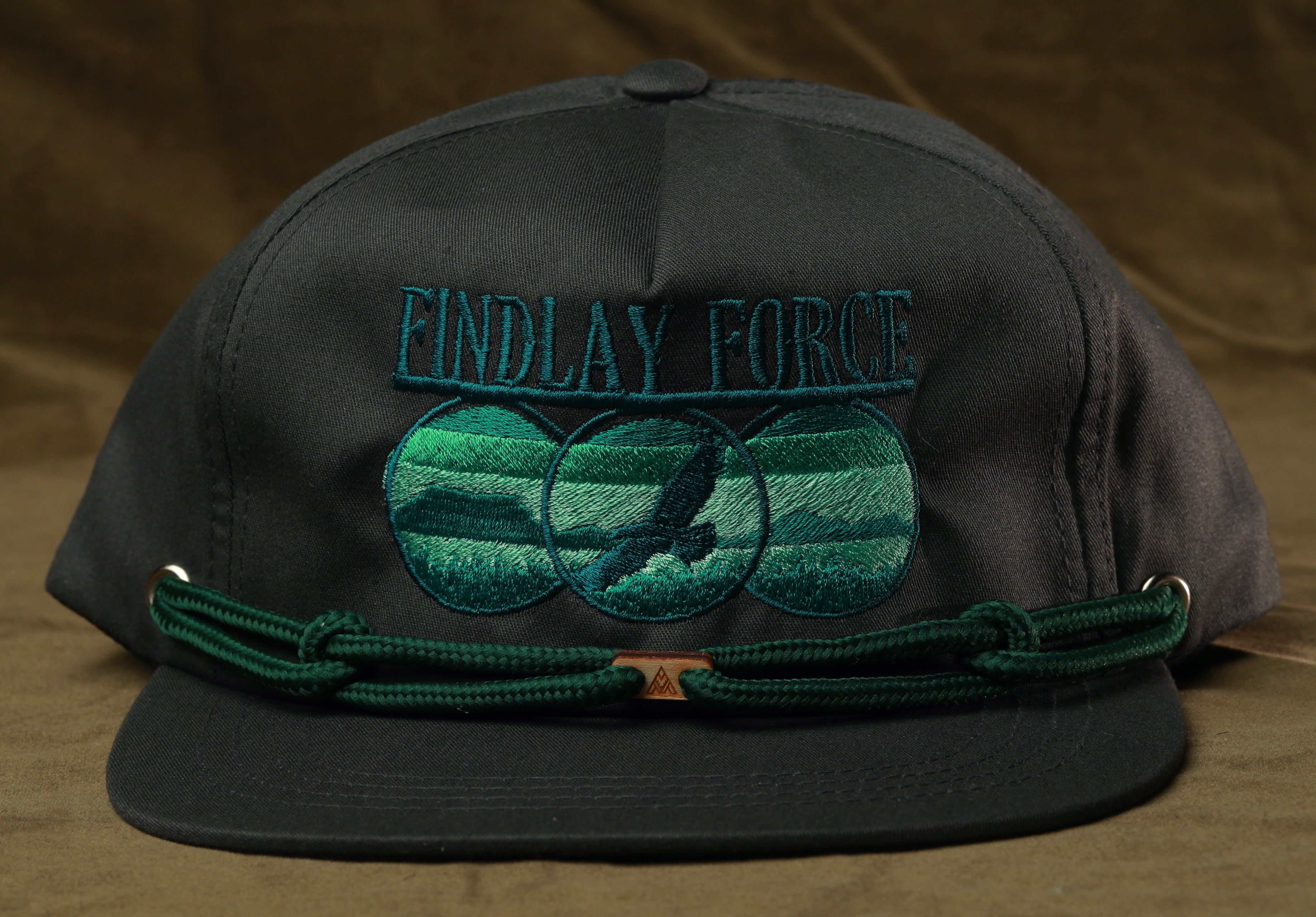 A black baseball cap with a green embroidered design and the text "FIND LAY FORCE" printed on it.