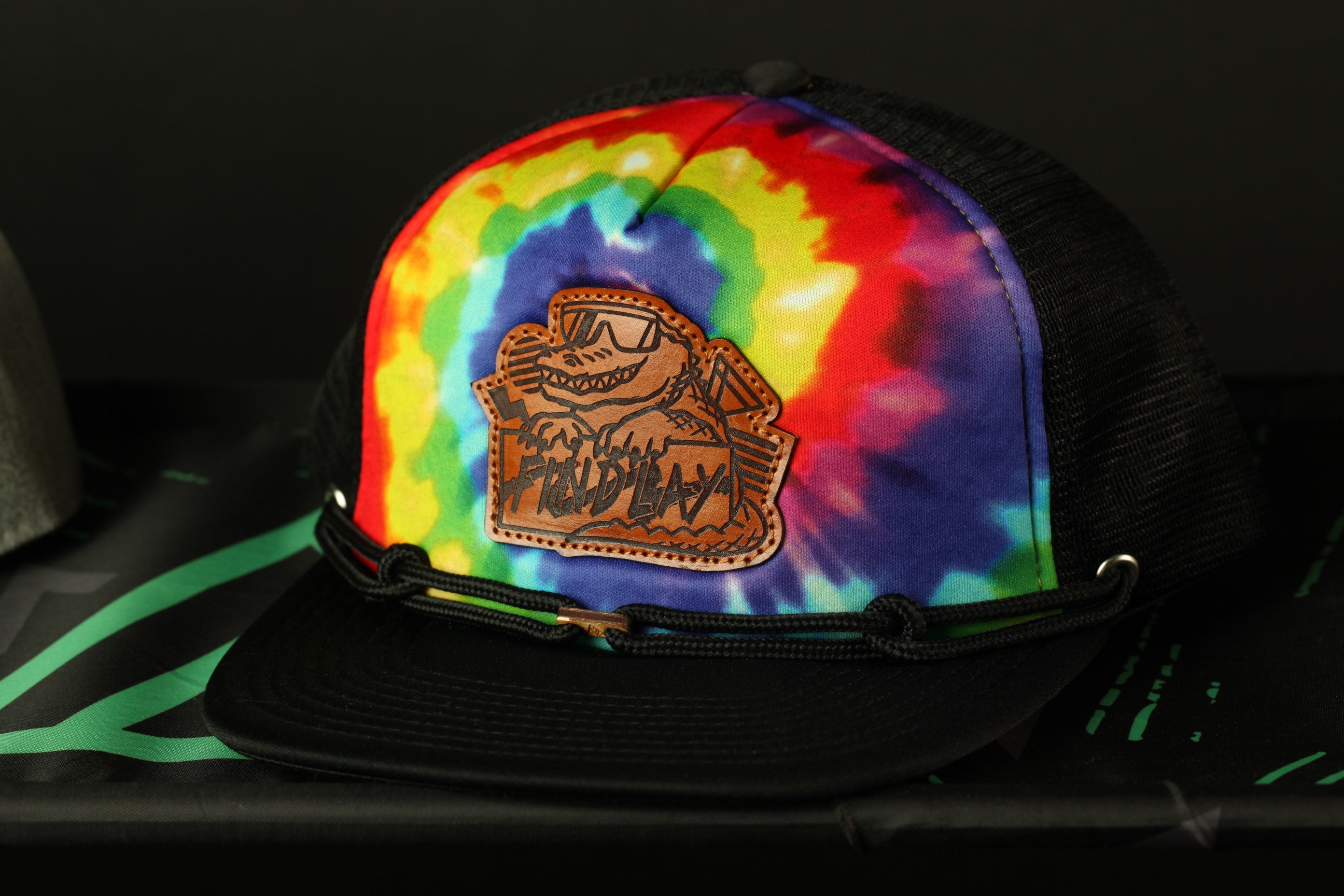 A colorful tie-dye baseball cap with a leather patch featuring a cartoon character.