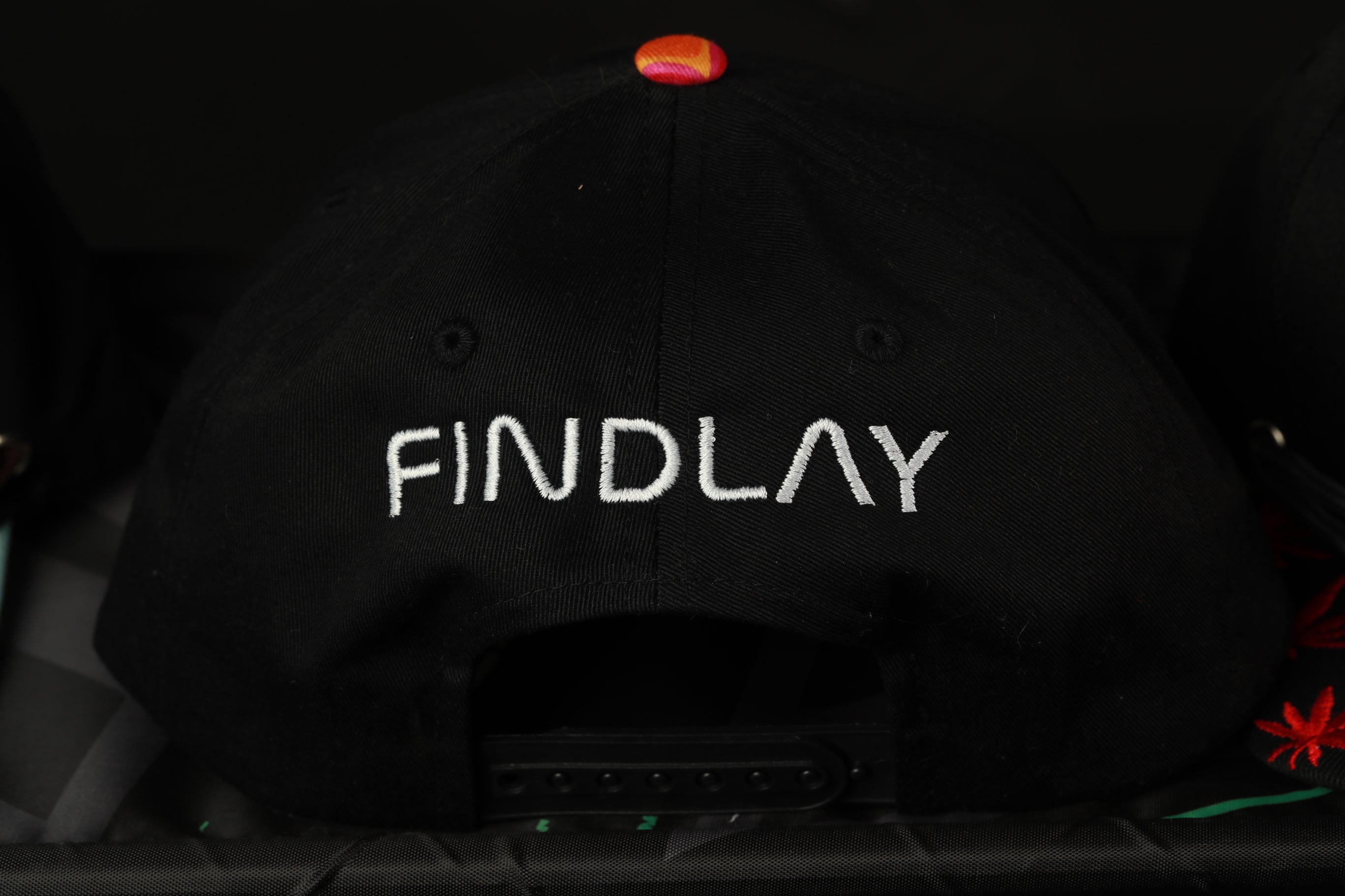 A black baseball cap with the word "FINDLAY" embroidered on it.
