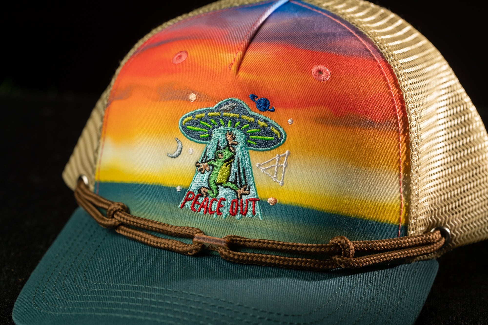 A colorful baseball cap with a peace sign and an alien character on the front.