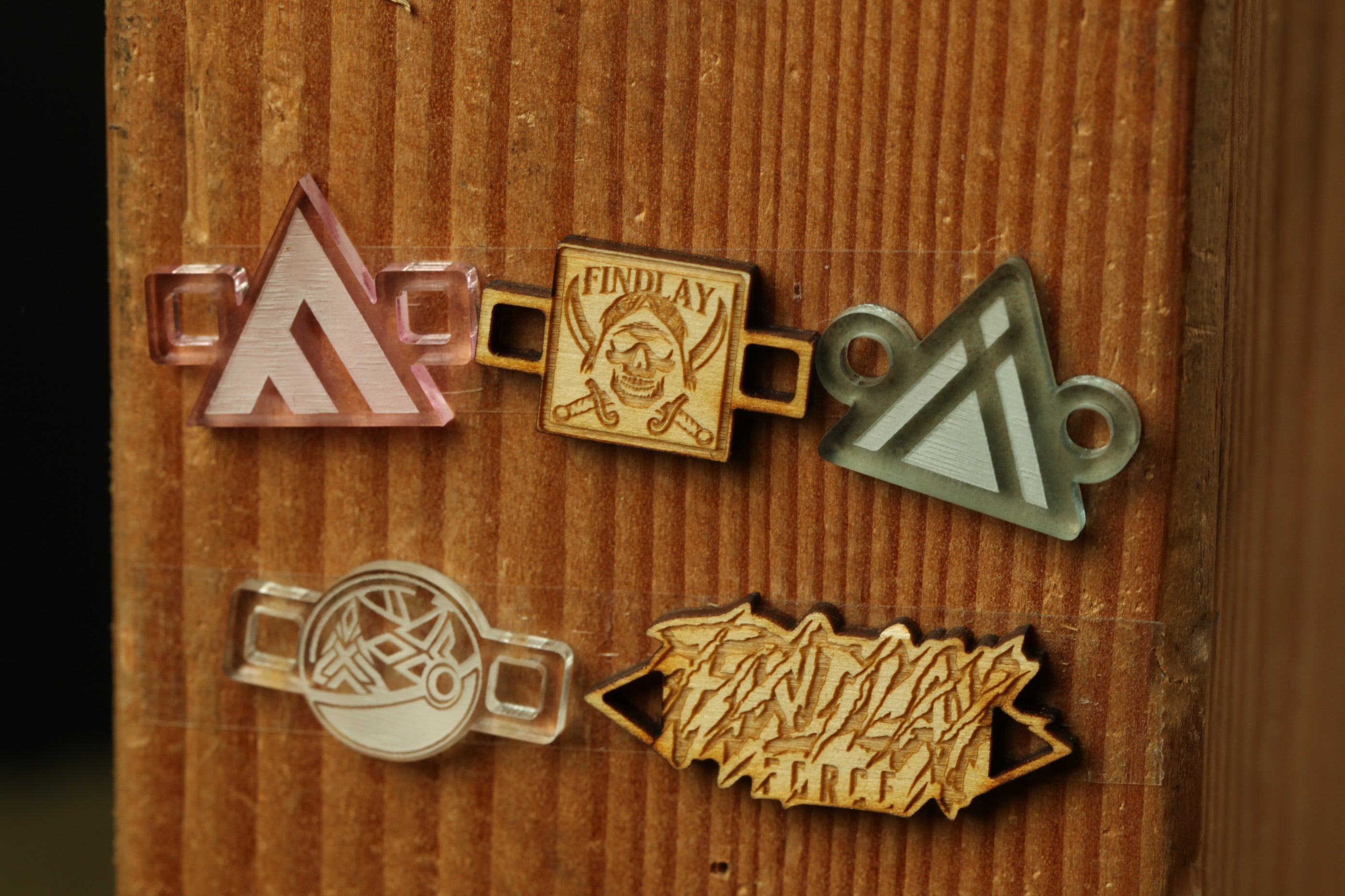 a wooden surface with various engraved and printed objects, including a triangular symbol, a skull and crossbones, and a circular emblem.