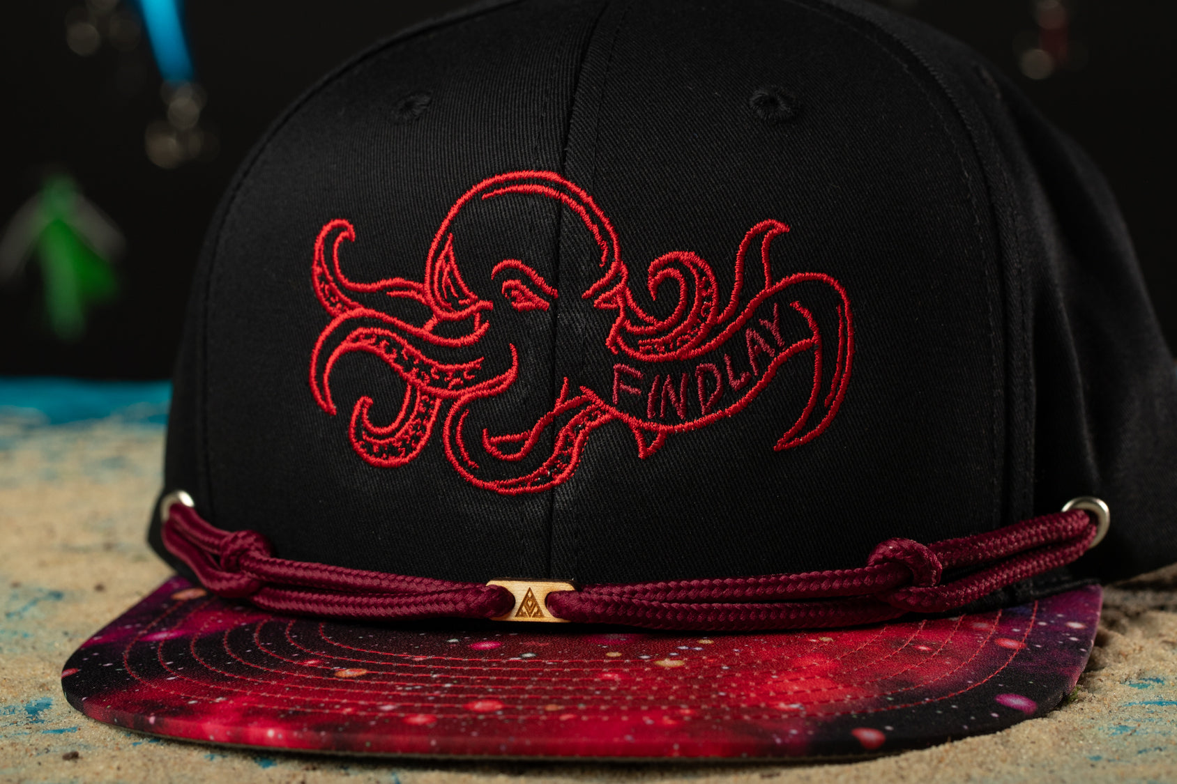 a black hat with a red octopus embroidered on it