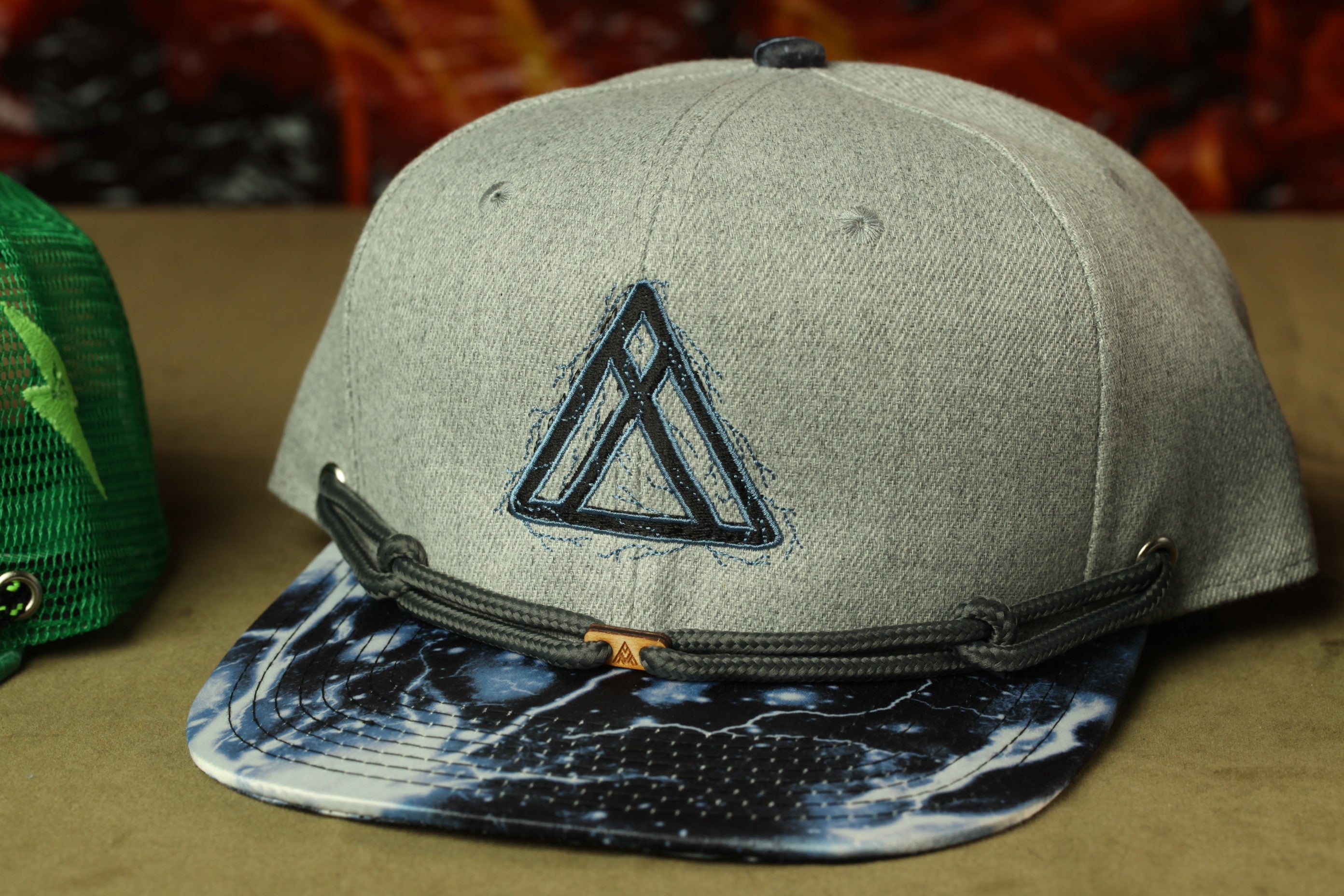 A gray baseball cap with a black triangle logo on the front, placed on a brown surface.