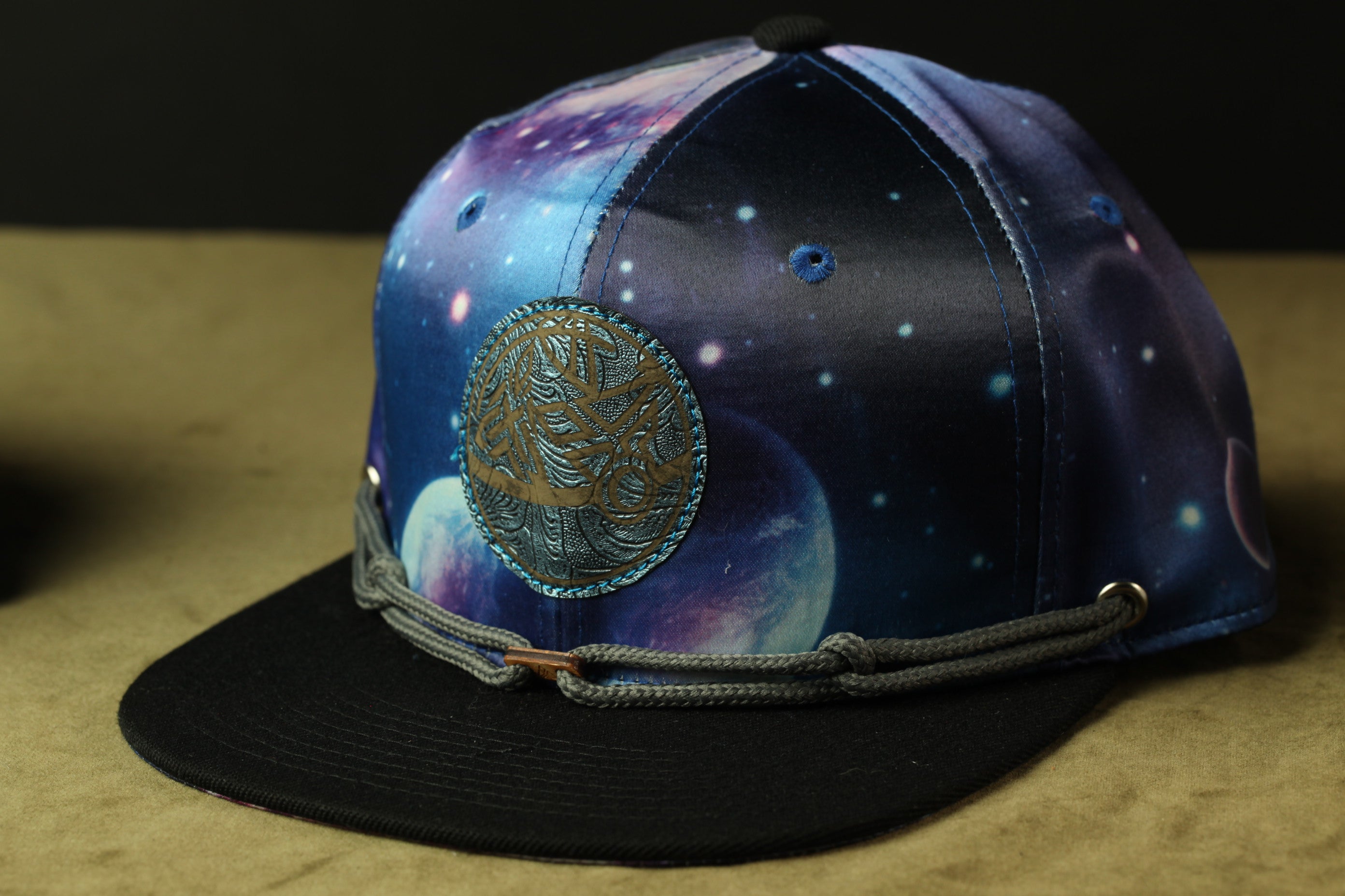 A black baseball cap with a colorful, space-themed design on the front.