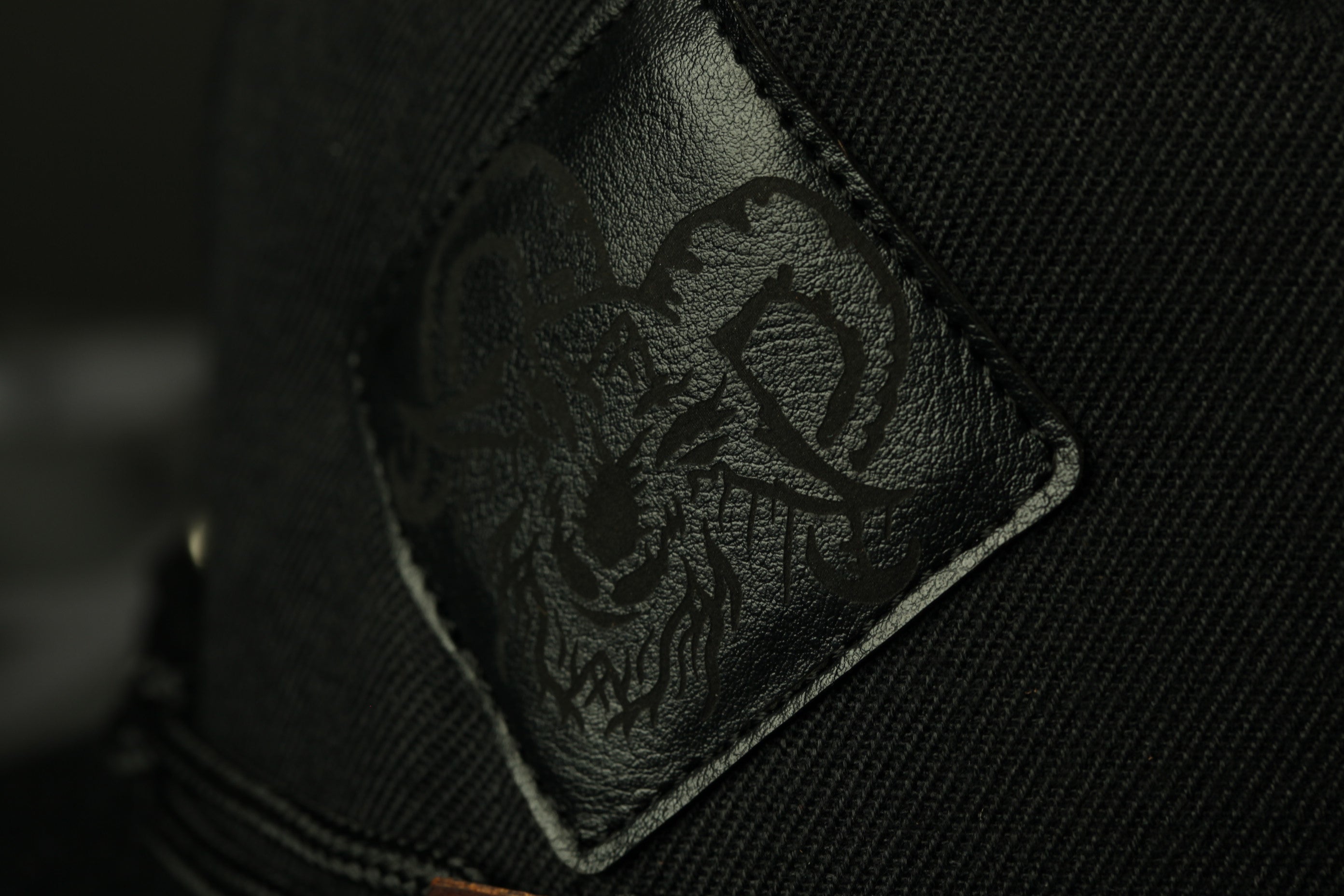 A close-up view of a black fabric with a detailed, embossed design featuring a stylized animal or creature.