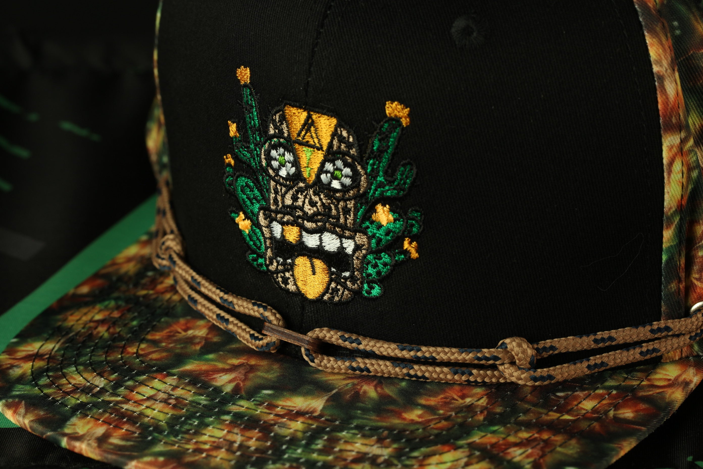 A close-up view of a black baseball cap with a colorful, embroidered design on the front.