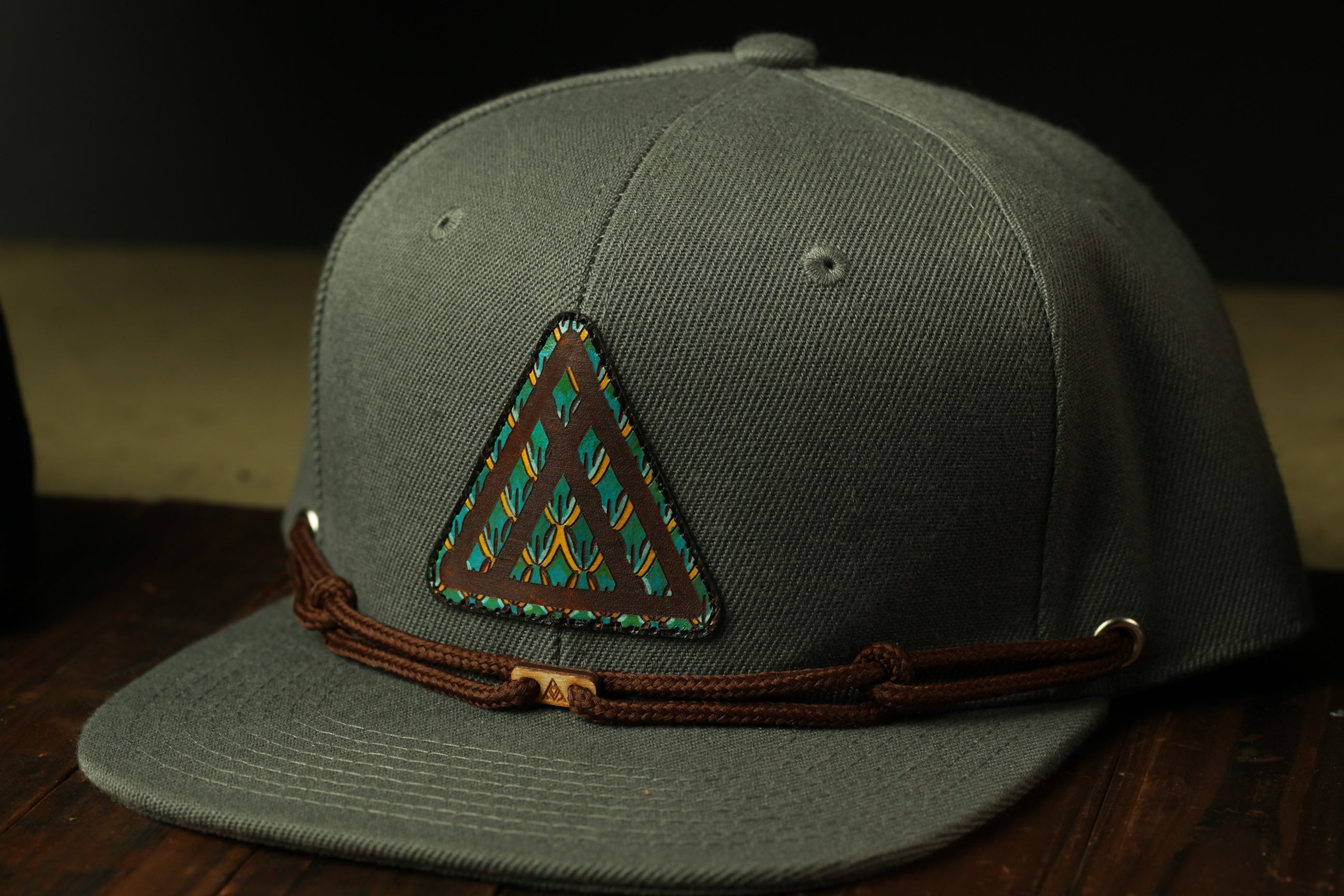 A gray baseball cap with a triangular patch featuring a colorful design on the front.