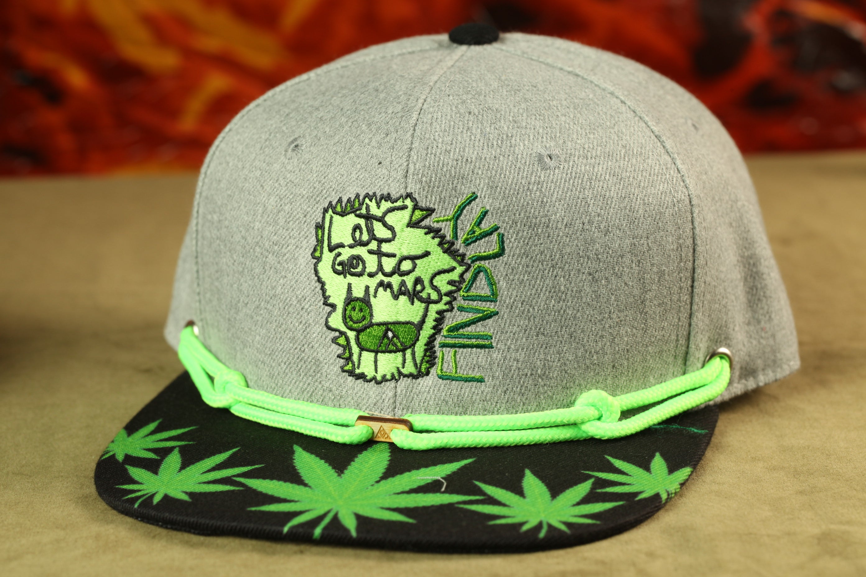 A grey baseball cap with a green and black design, featuring a cartoon-style character and the text "Let's go to mars" on the front.