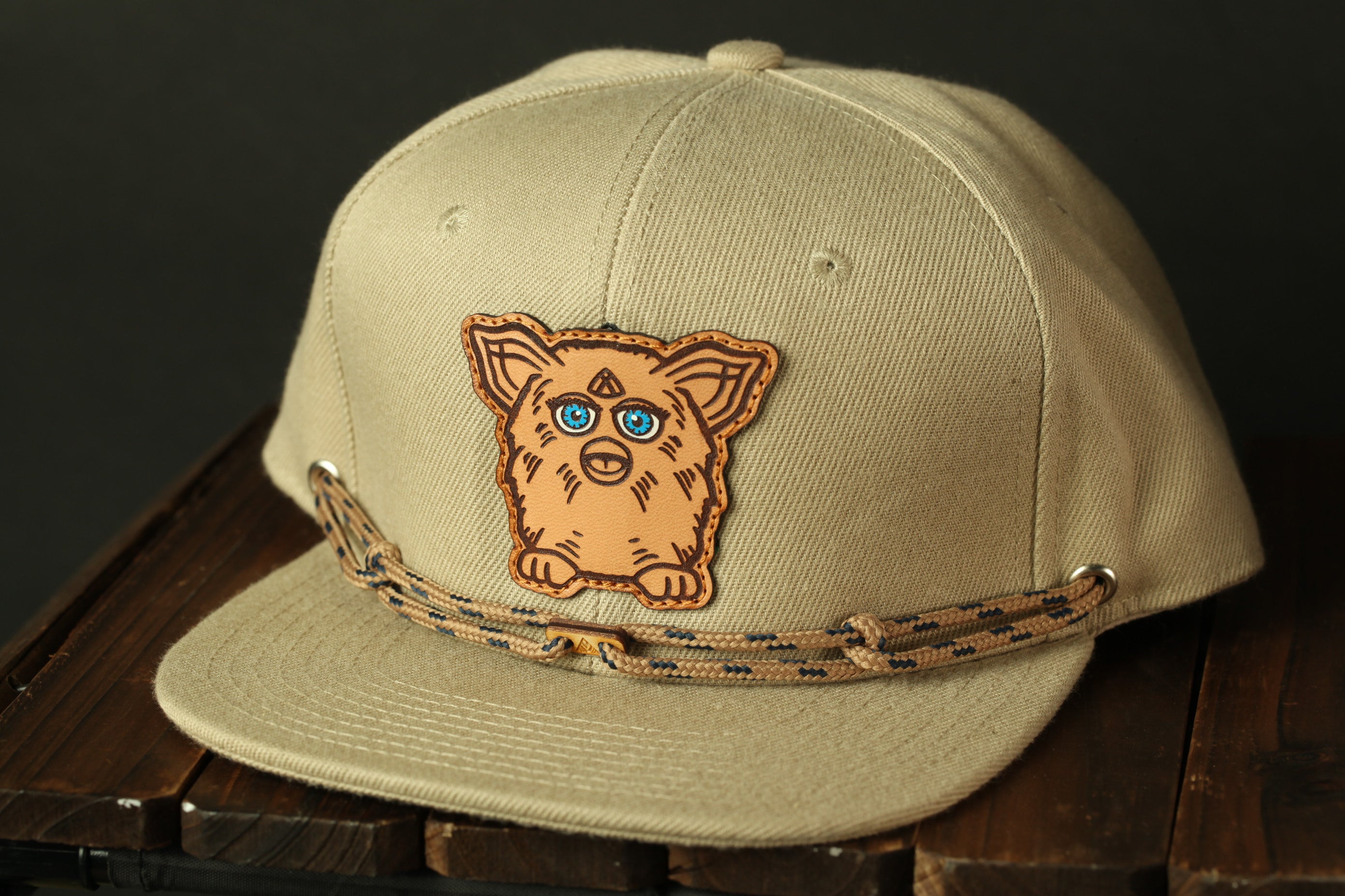 A beige baseball cap with a cartoon character design on the front.