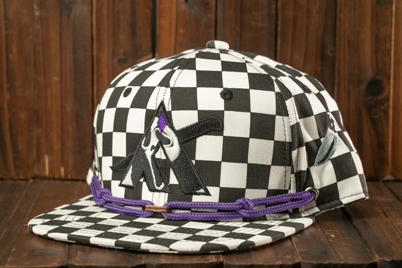 A black and white checkered baseball cap with a purple string and a graphic design on the front.