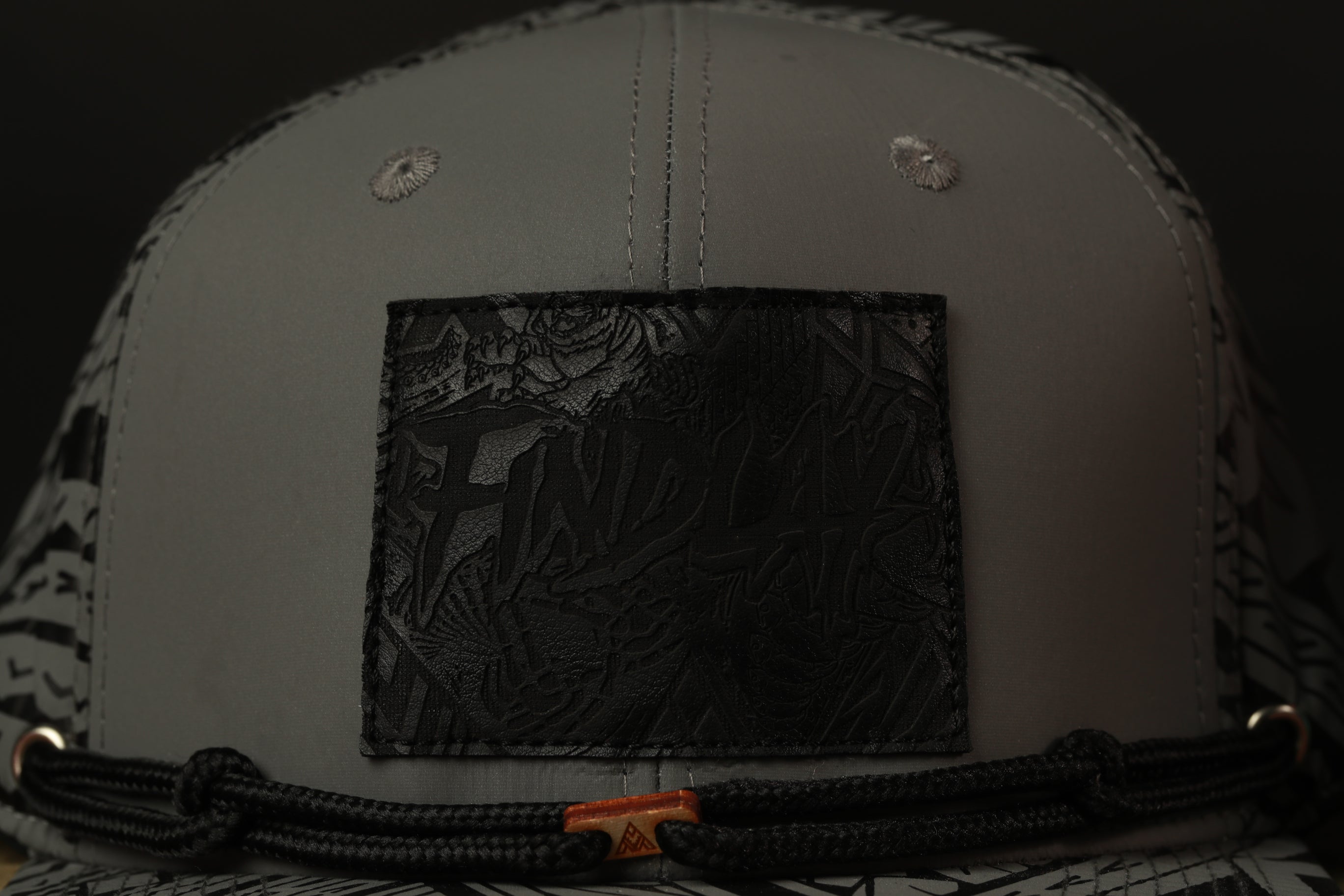 a close-up view of a gray baseball cap with a black patch on the front.
