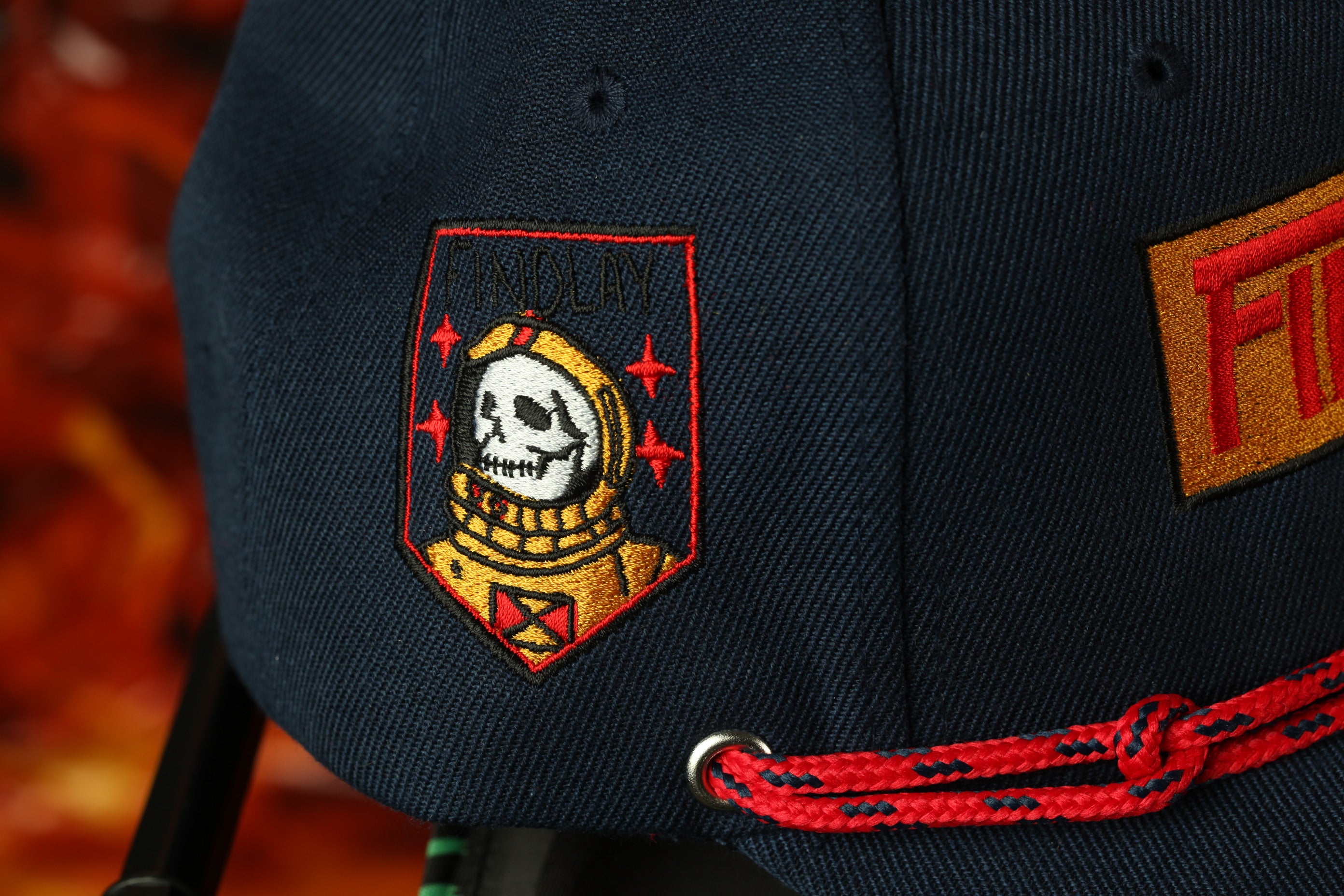 a close-up view of a dark blue baseball cap with a distinctive skull and crossbones design on the front.