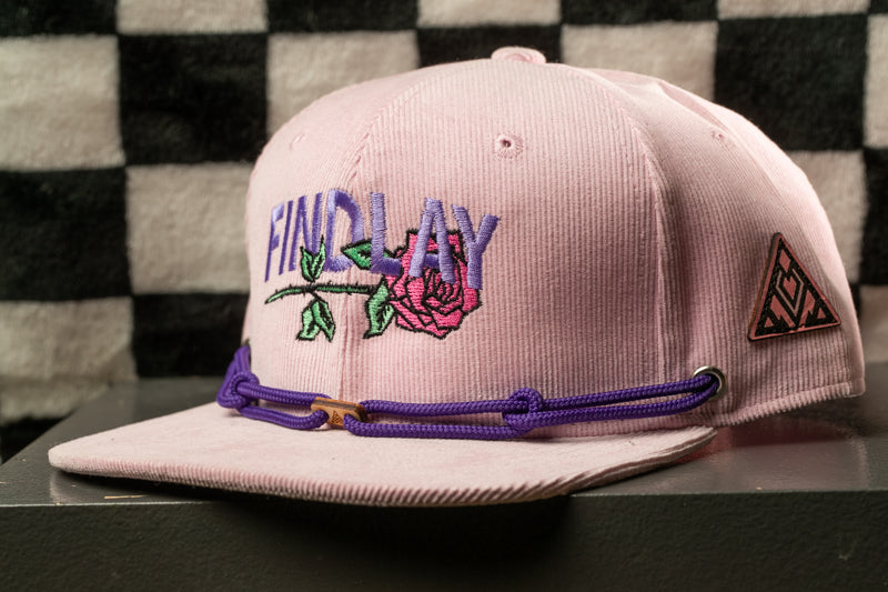 A pink baseball cap with purple and green embroidered designs, including a rose and the word "FINDLAY".