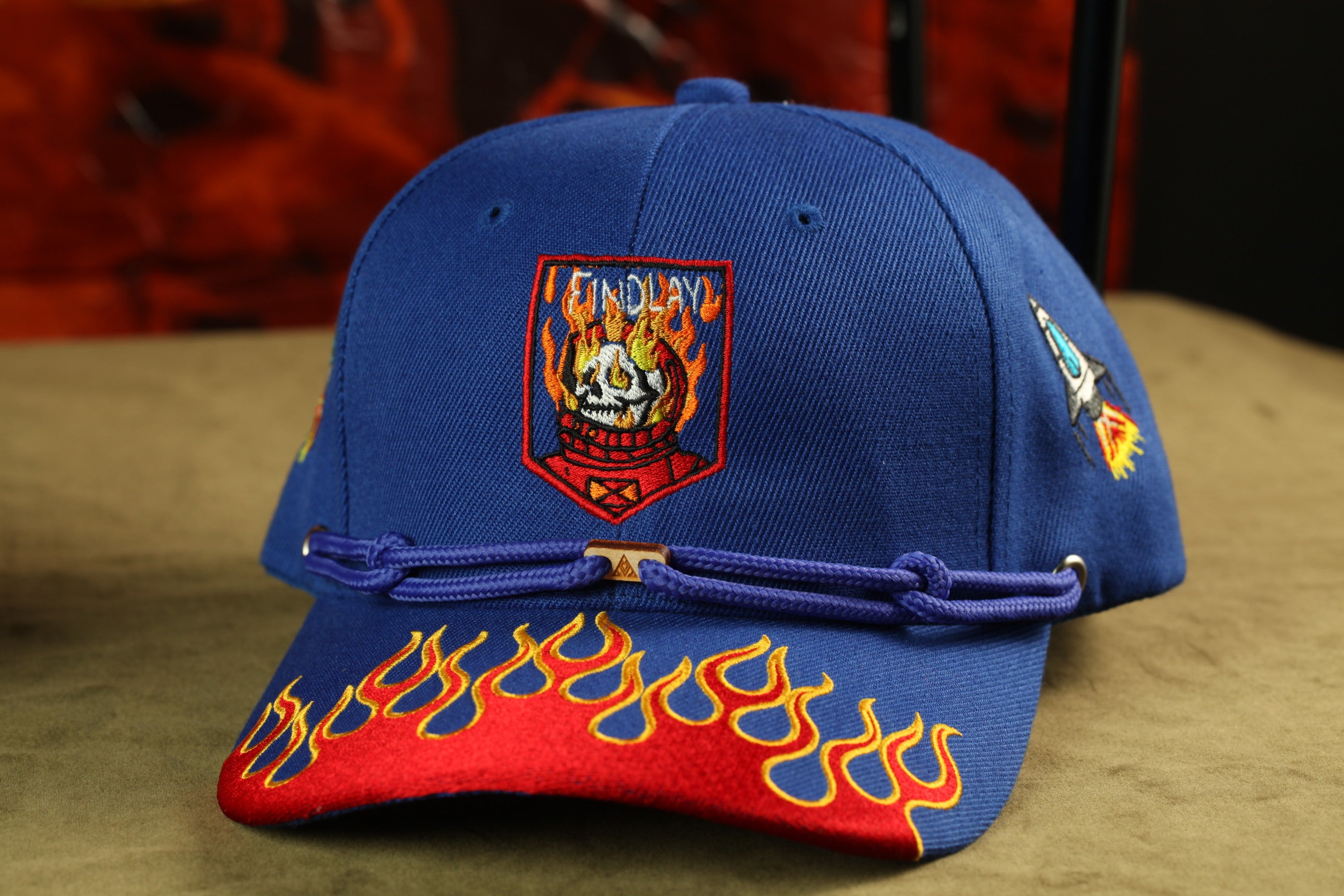 A blue baseball cap with a flame design on the front and a red and yellow flame design on the brim.