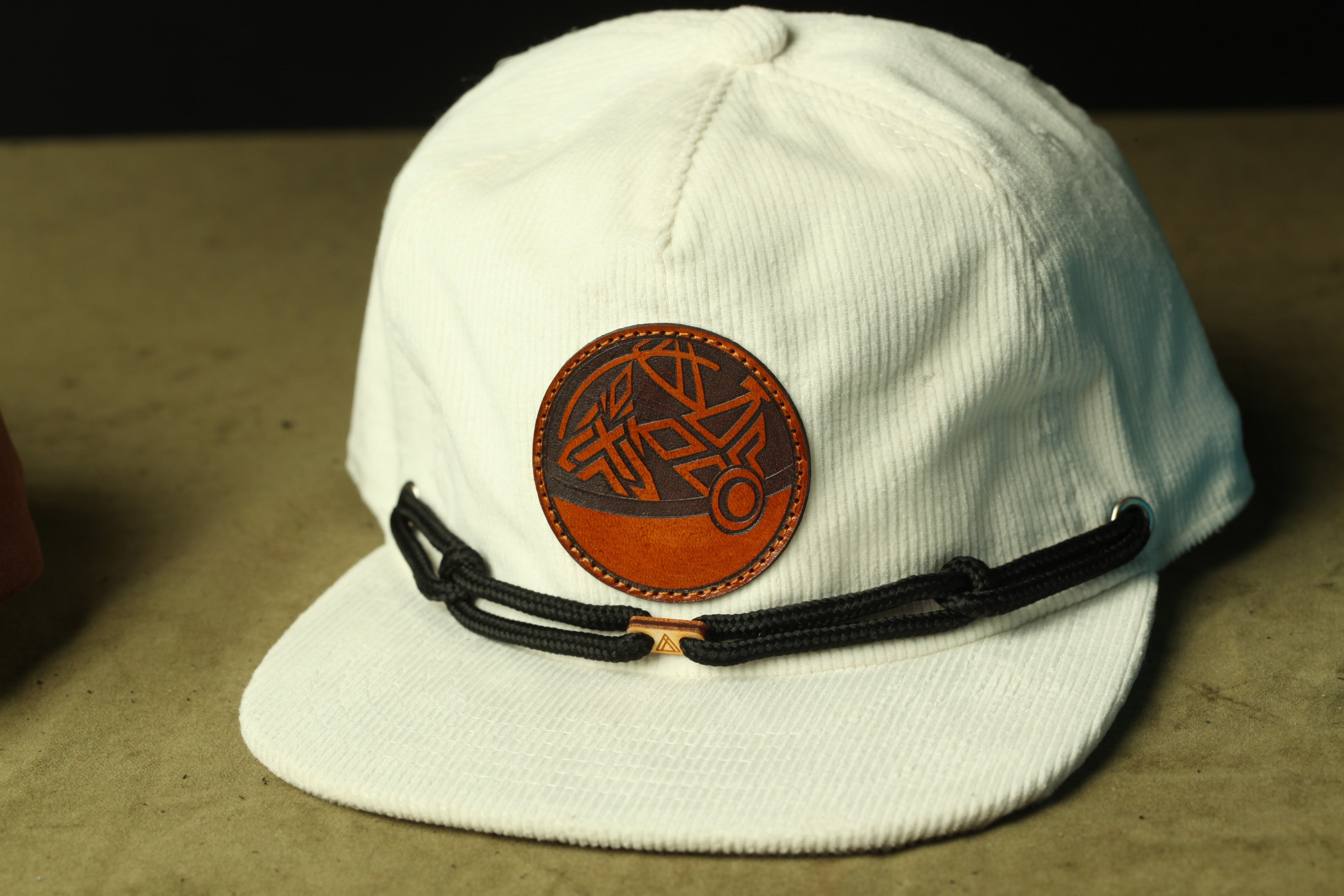 A white baseball cap with a circular leather patch on the front.