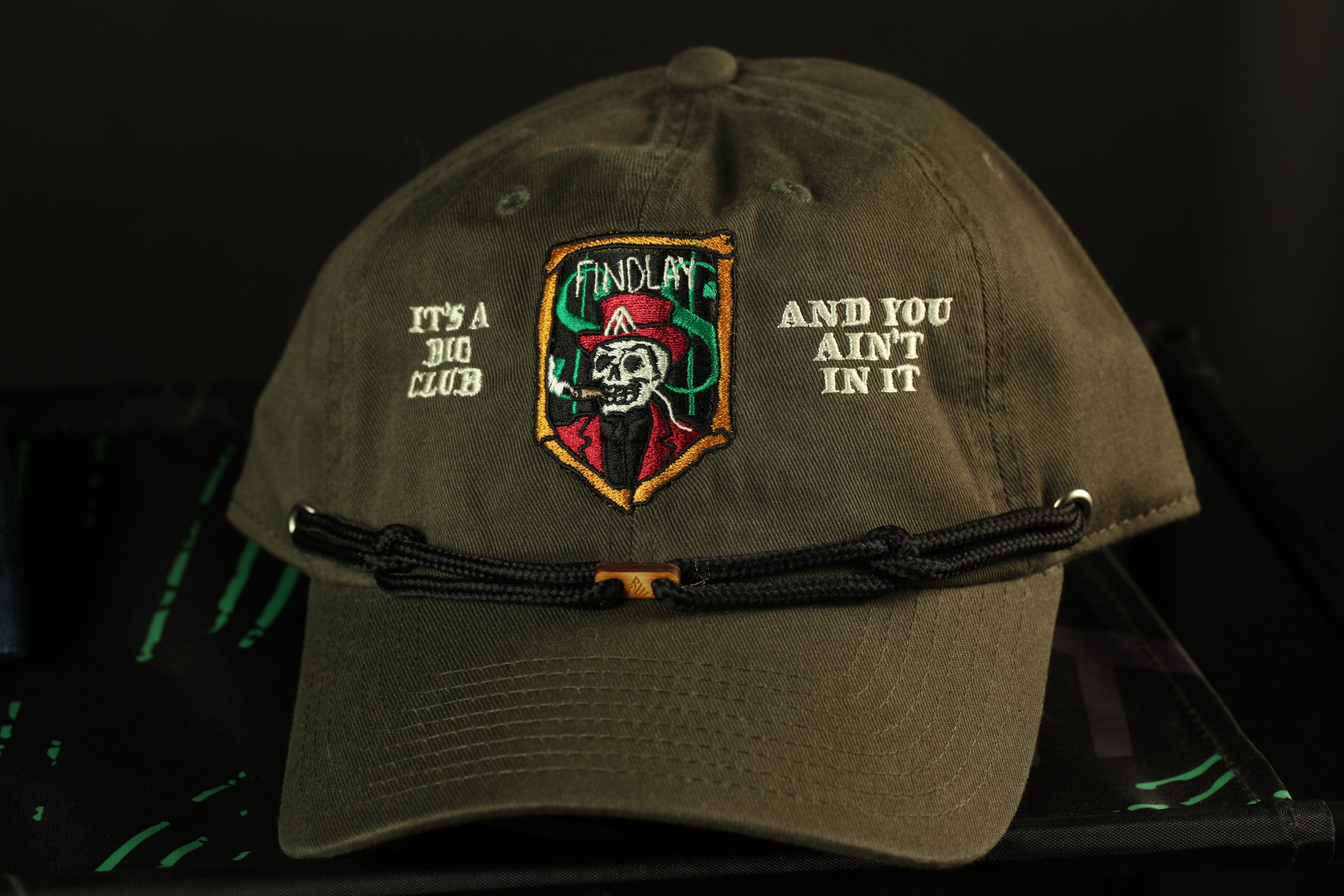 A dark green baseball cap with a skull and crossbones design, and text on the front.