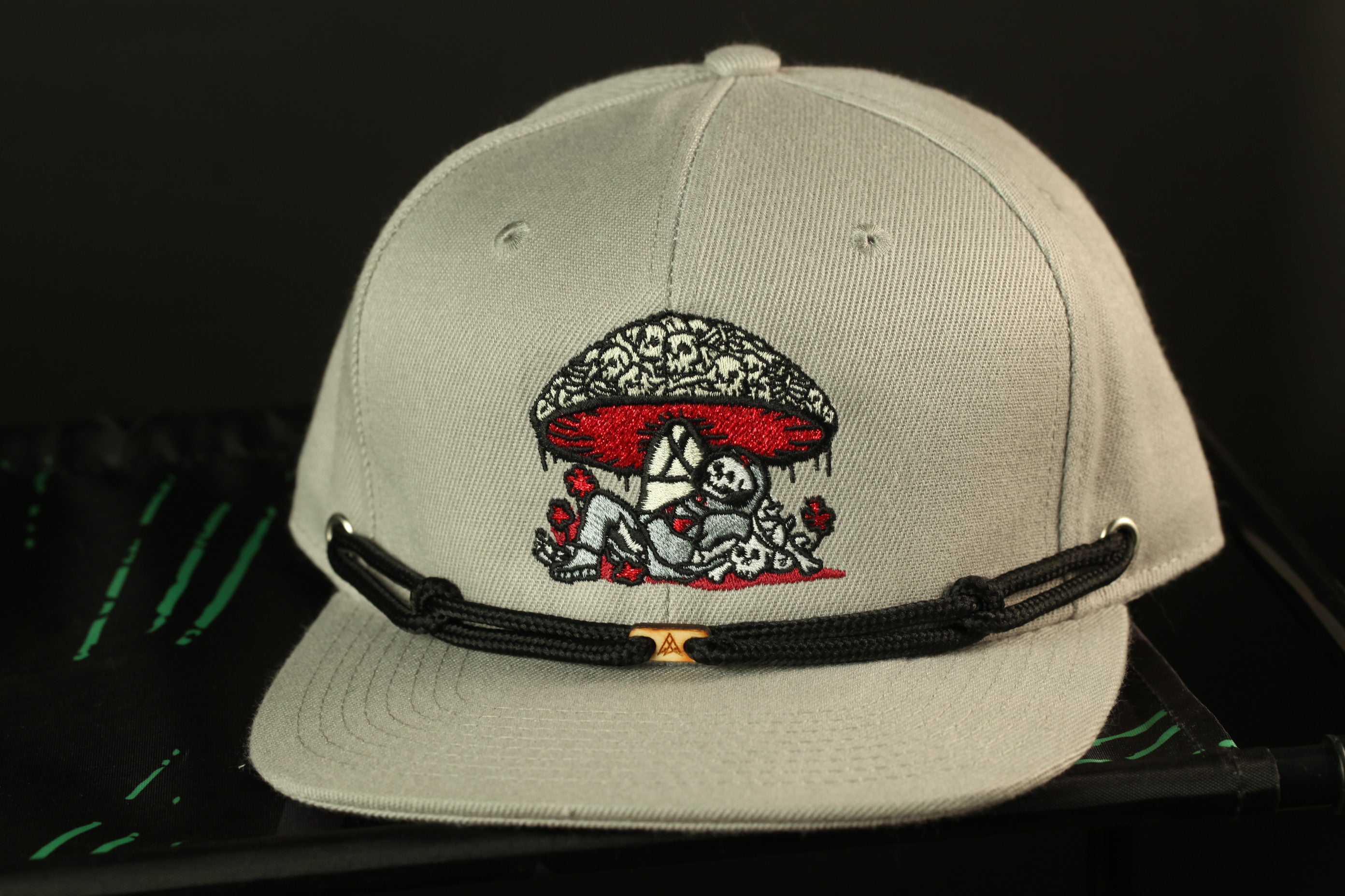 A gray baseball cap with a black strap and an embroidered design on the front.