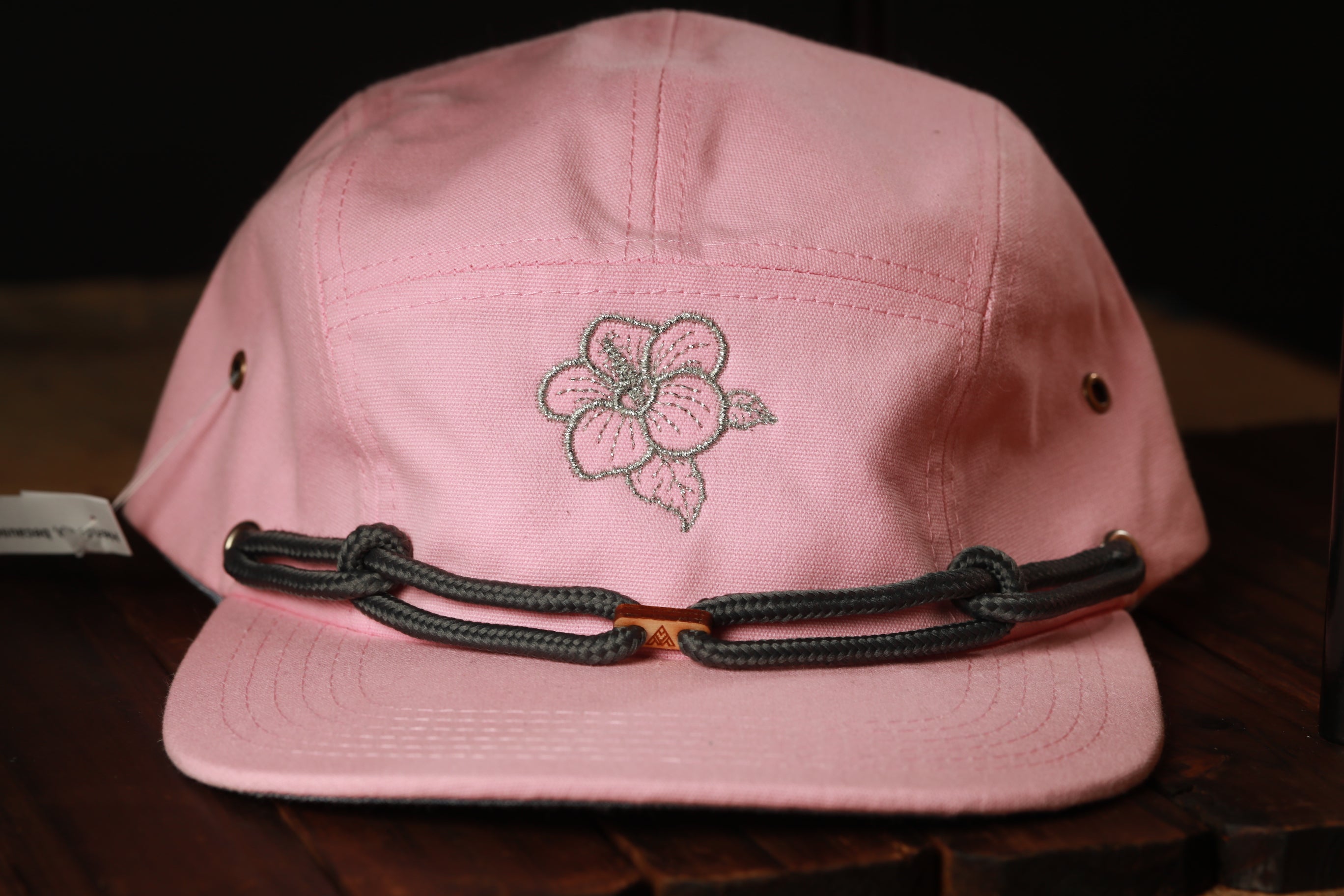A pink baseball cap with a floral embroidered design on the front.