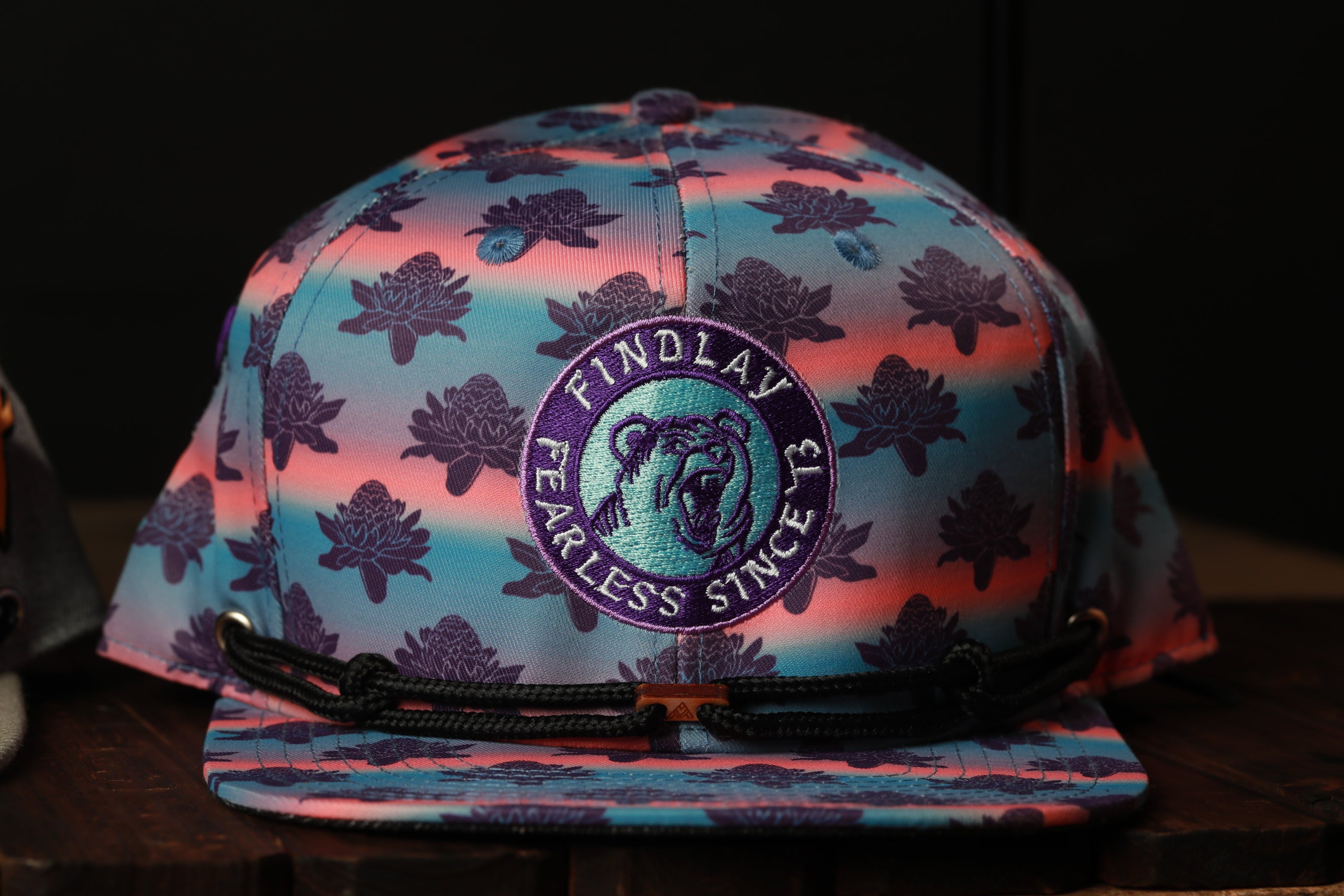 A colorful baseball cap with a floral pattern and a circular logo on the front.