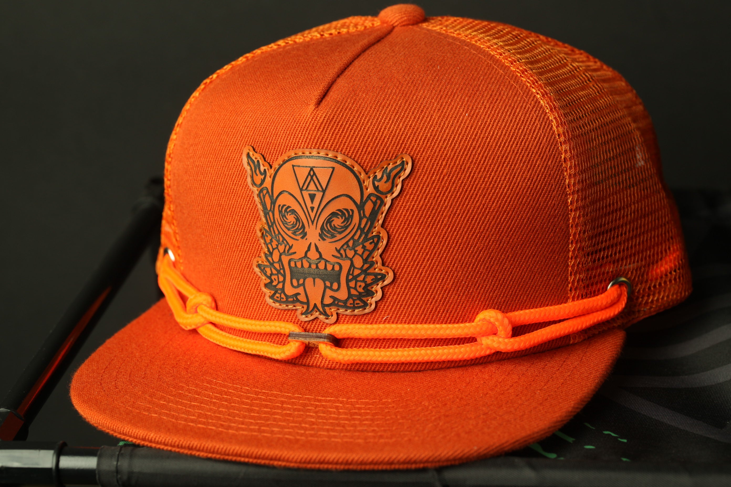 An orange baseball cap with a black skull and crossbones design on the front.