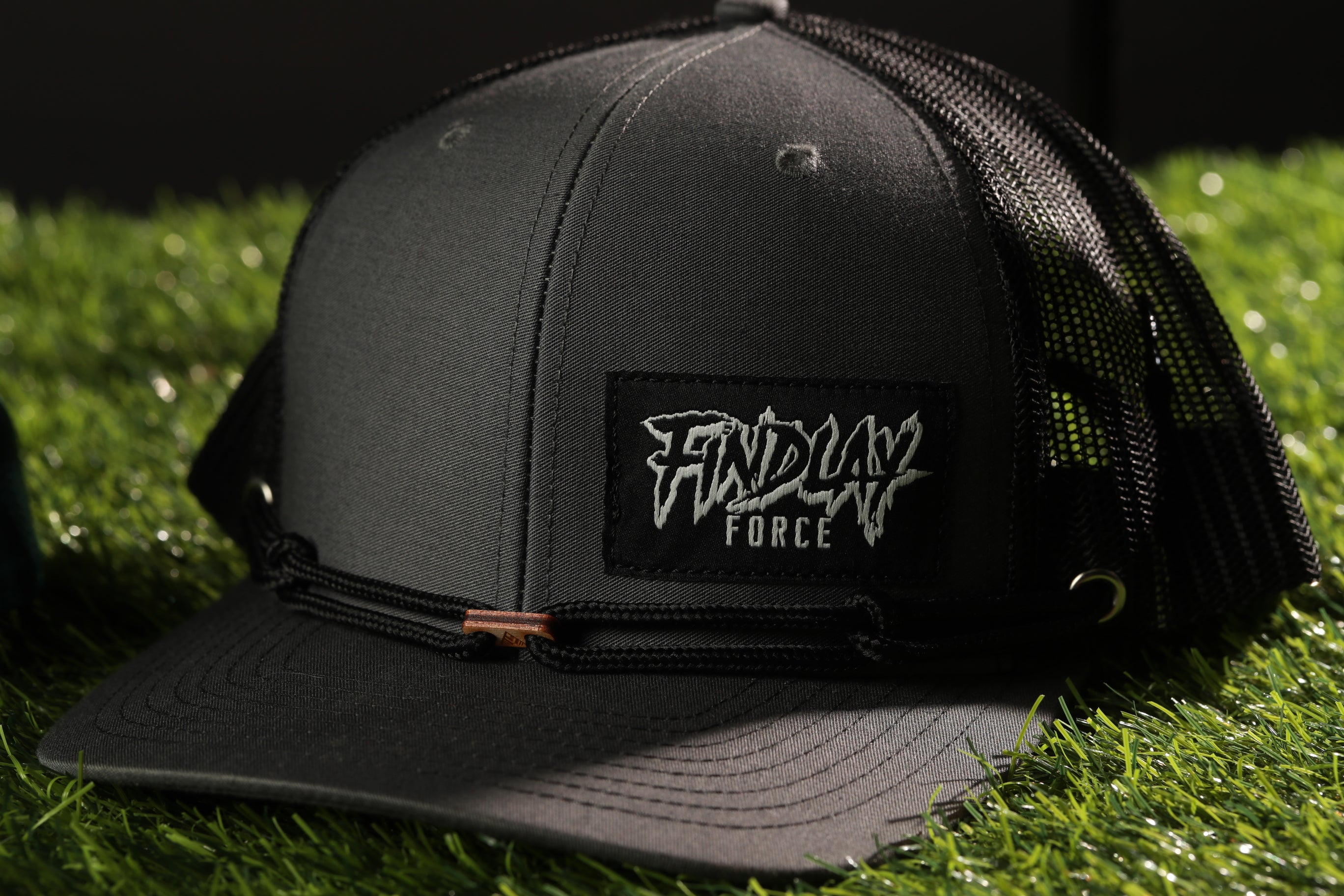 A black baseball cap with a mesh back, placed on a grassy surface.
