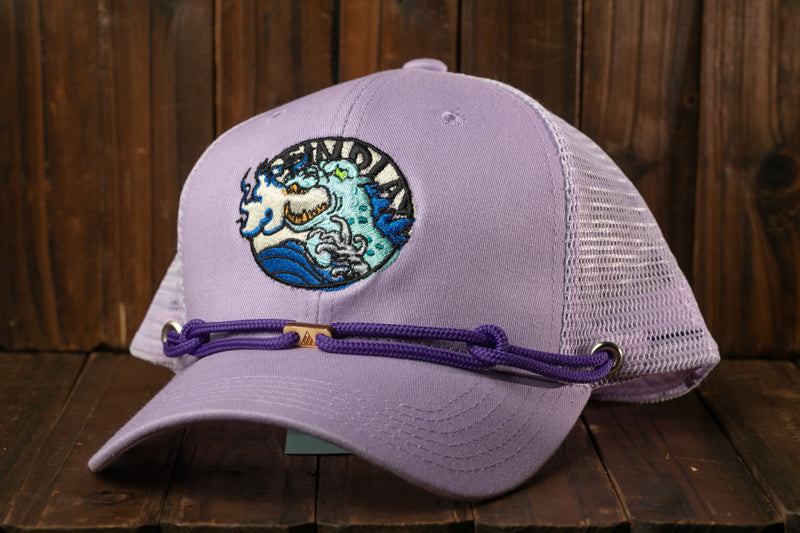 A purple baseball cap with a circular embroidered logo on the front, sitting on a wooden surface.