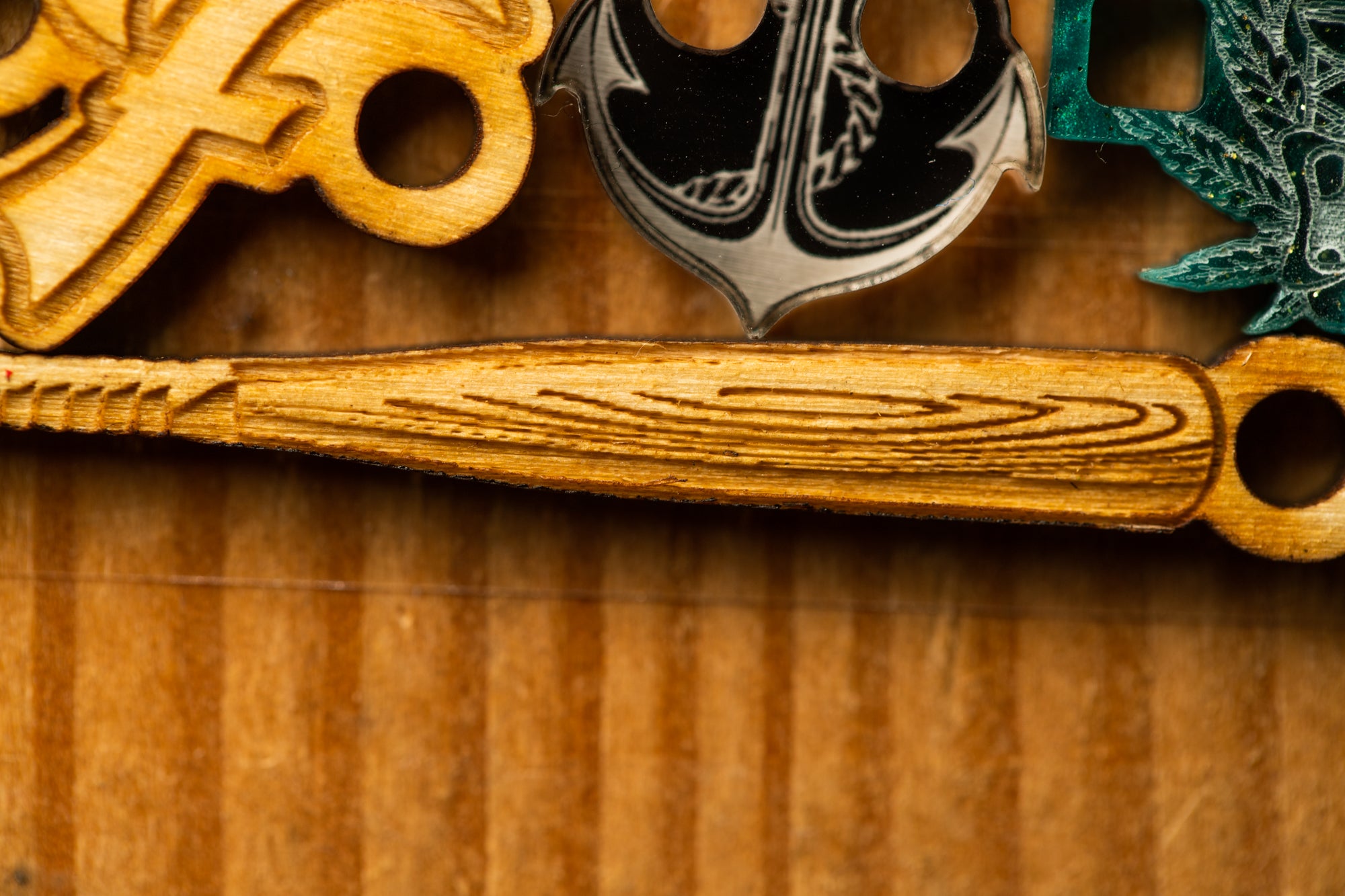 a wooden baseball bat with a unique design, including a black anchor and a green leaf-like object.