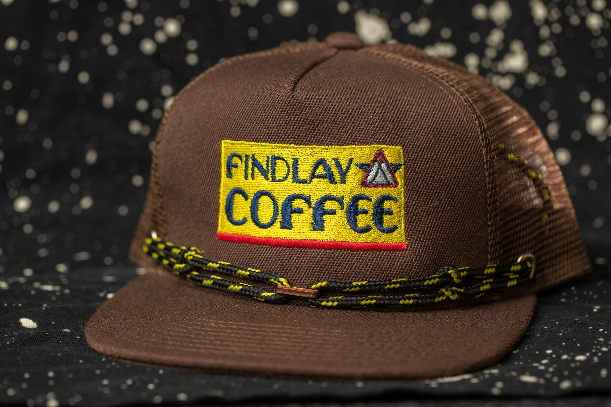 A brown baseball cap with a yellow patch that says "FINDLAY COFFEE".