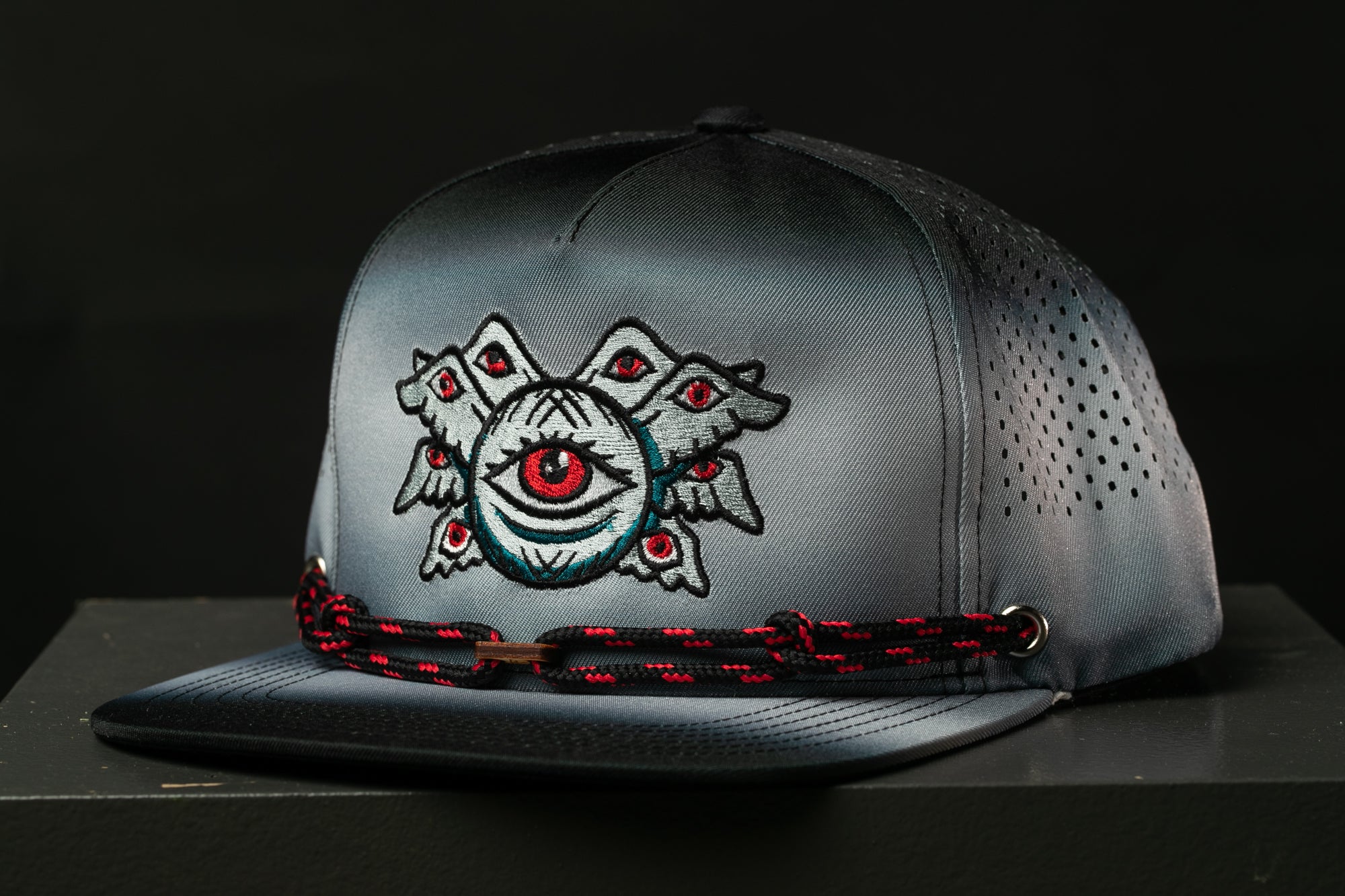A gray baseball cap with a unique eye design on the front.