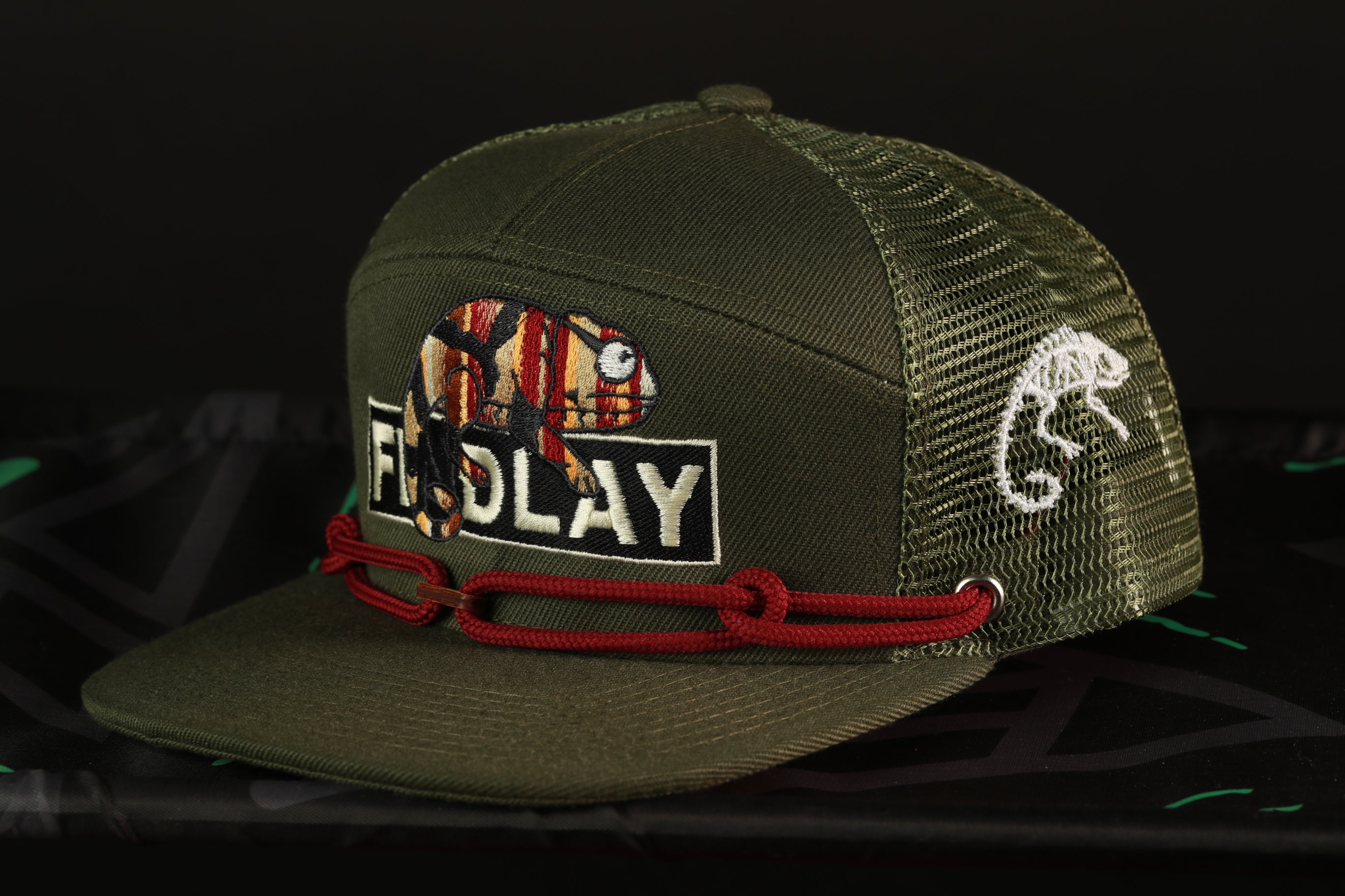 A green baseball cap with a mesh back and a red string around the brim.
