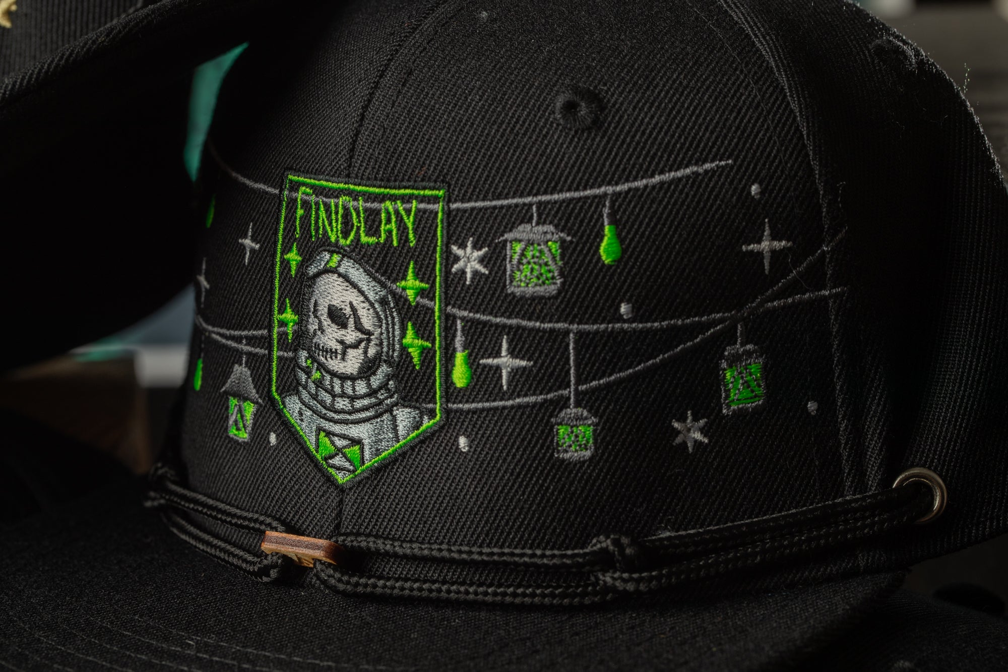 a close-up view of a black baseball cap with a unique embroidered design on the front.