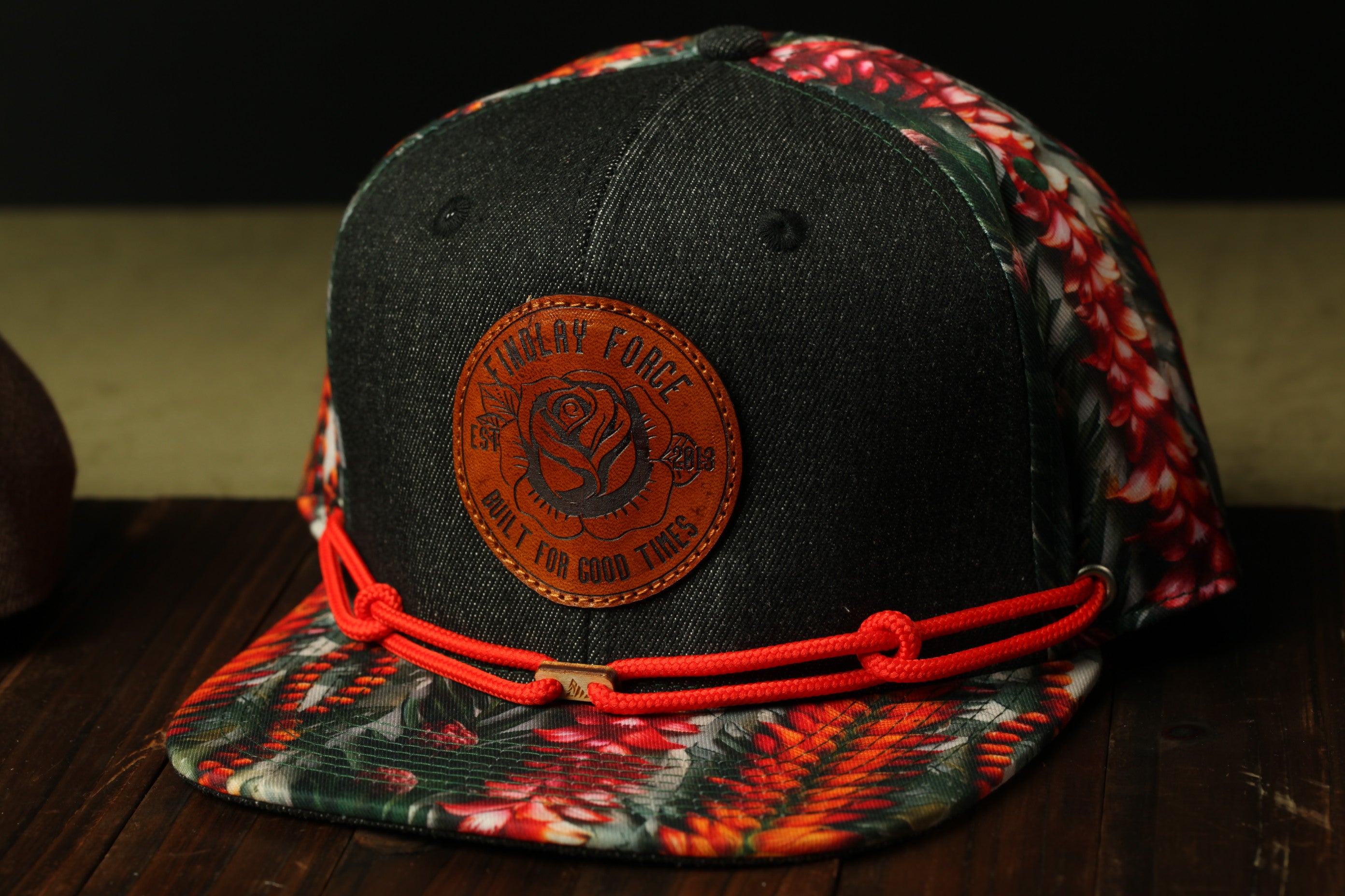 A black baseball cap with a floral print and a circular patch on the front, featuring a rose design and the text "FINAL V" and "BUILD I FOR GOOD TIMES".