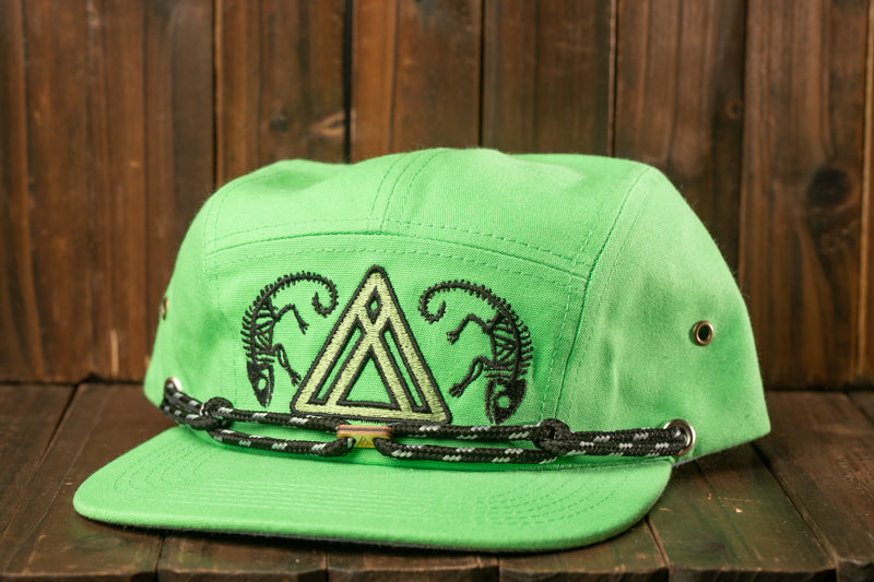 A lime green baseball cap with a black and white chain strap and a triangle-shaped logo on the front, placed on a wooden surface.