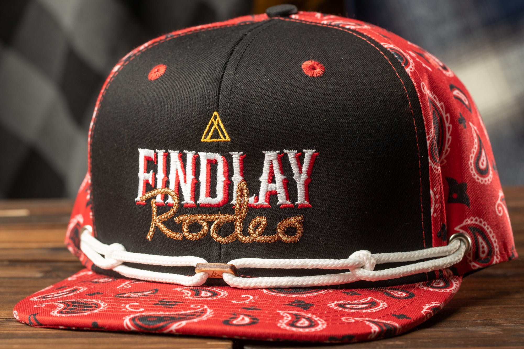A black baseball cap with red and white paisley patterns, featuring the text "FINDlay Rodeo" embroidered on it.
