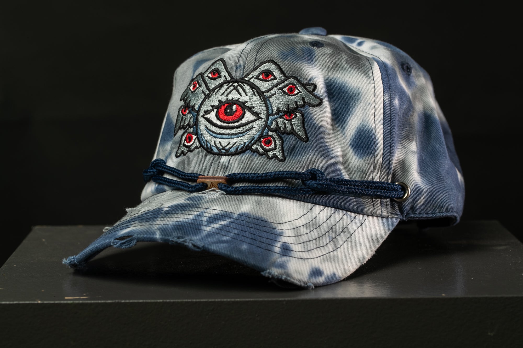 A worn blue and white baseball cap with an eye design on the front.