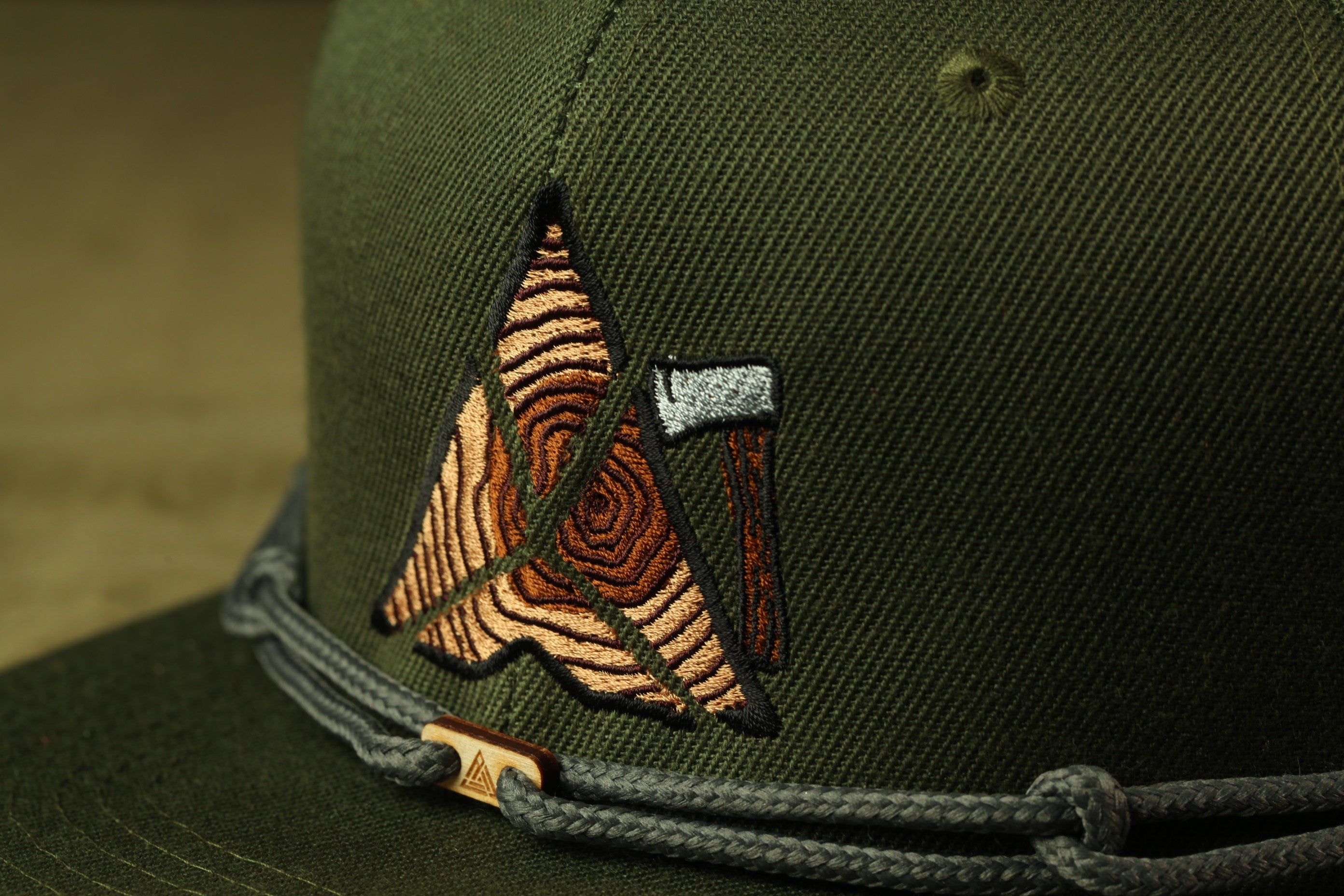 A close-up view of a green baseball cap with a unique embroidered logo on the front.