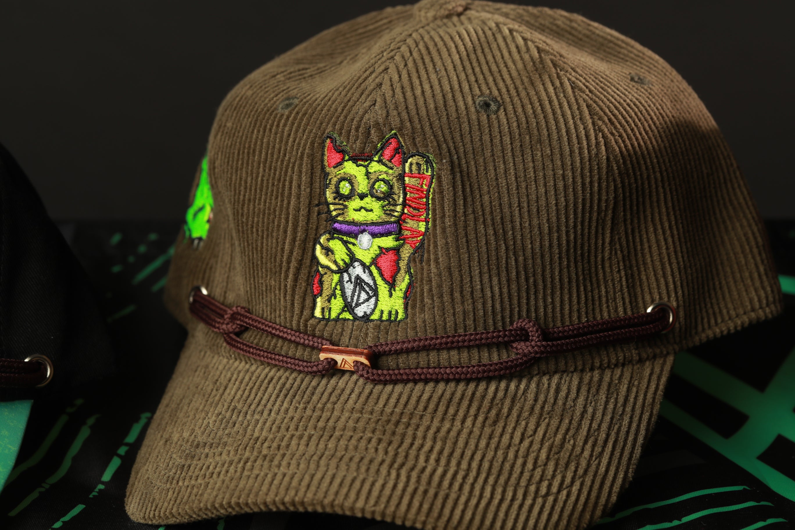 A brown baseball cap with a colorful cat embroidered on it.